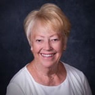 A woman in a white shirt is smiling for the camera.