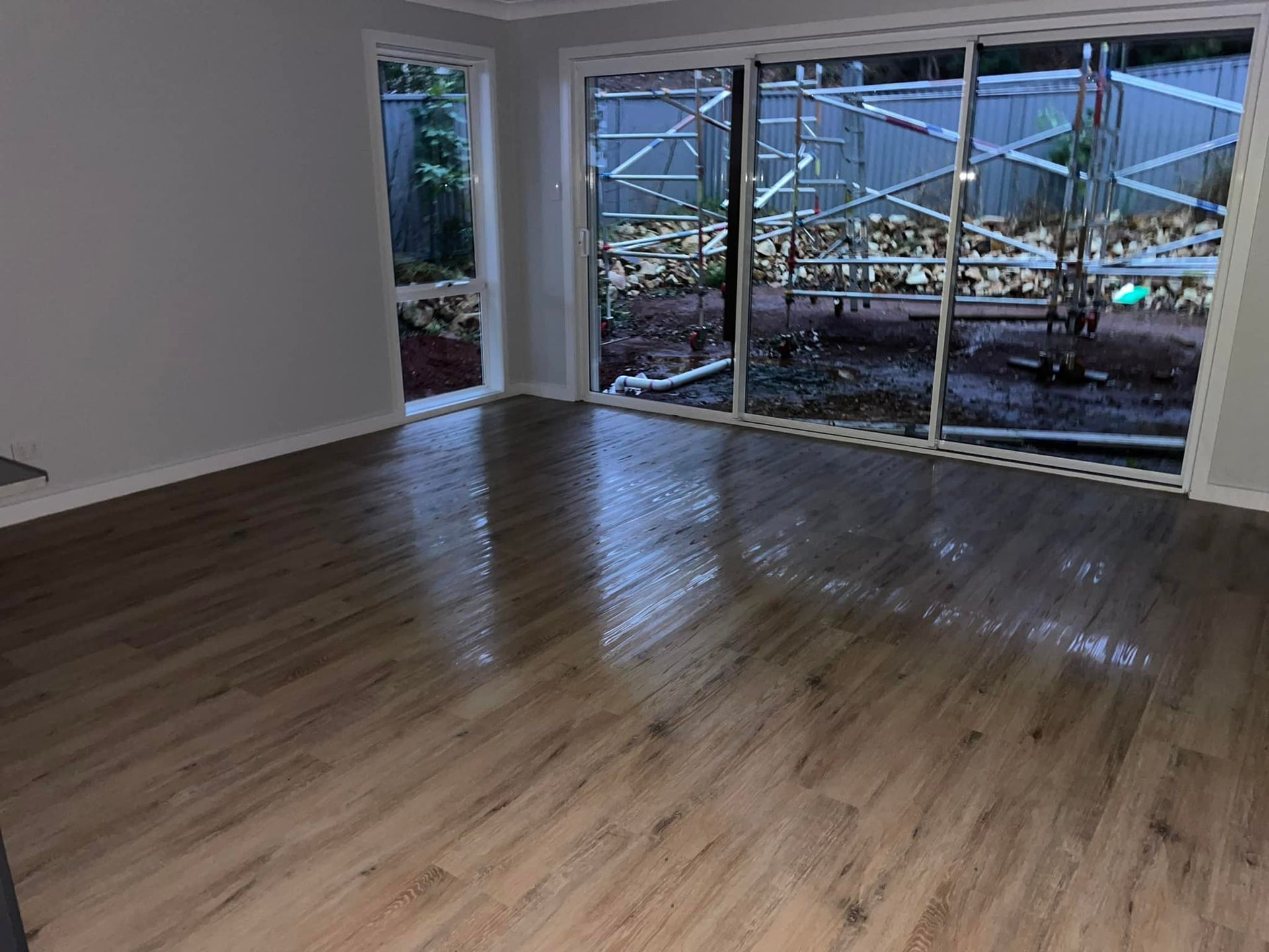 An Empty Living Room With Hardwood Floors and Sliding Glass Doors — Doobies Cleaning Service in Kempsey, NSW