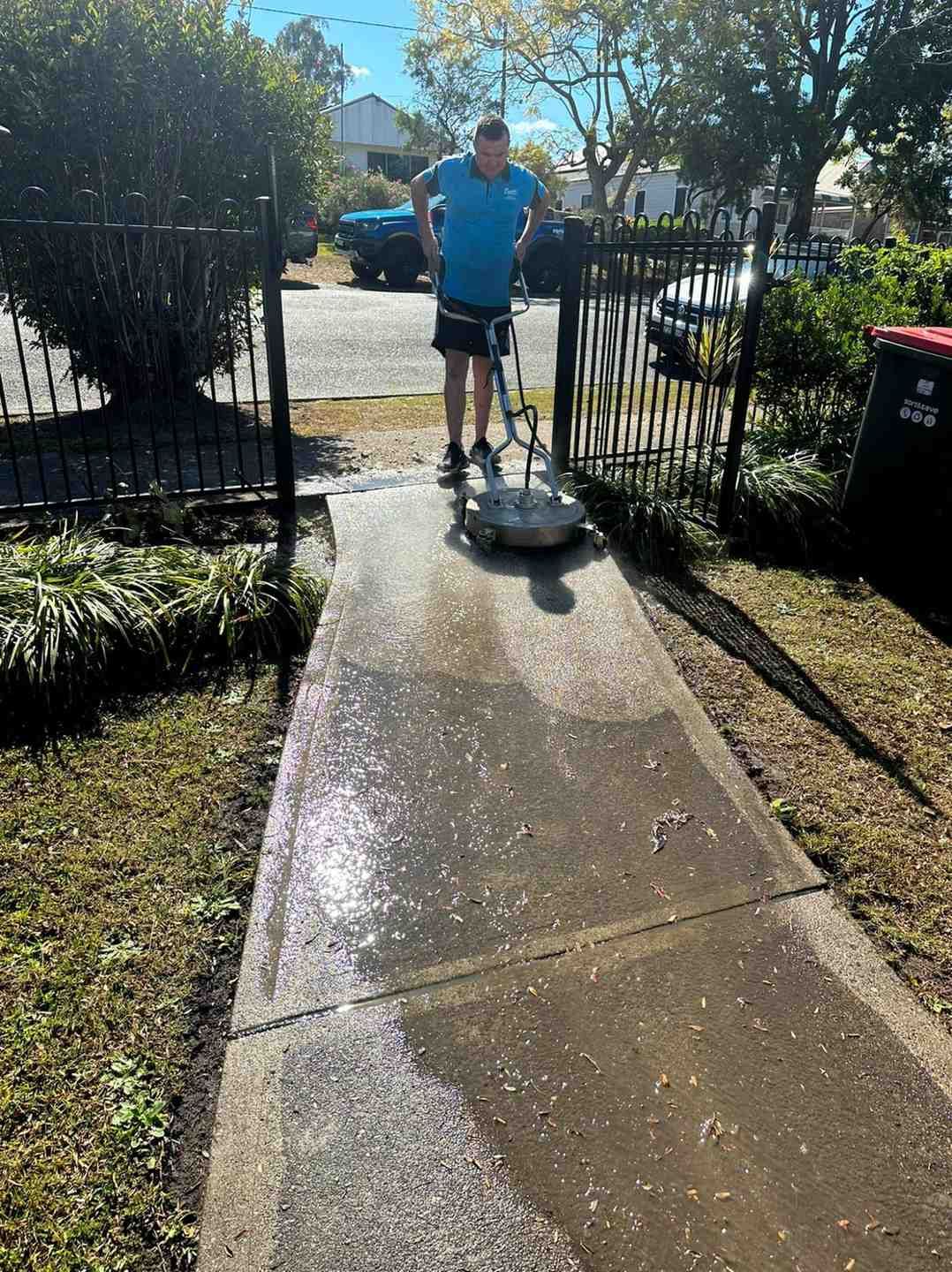 A Man is Cleaning a Sidewalk With a Machine — Doobies Cleaning Service in Port Macquarie, NSW
