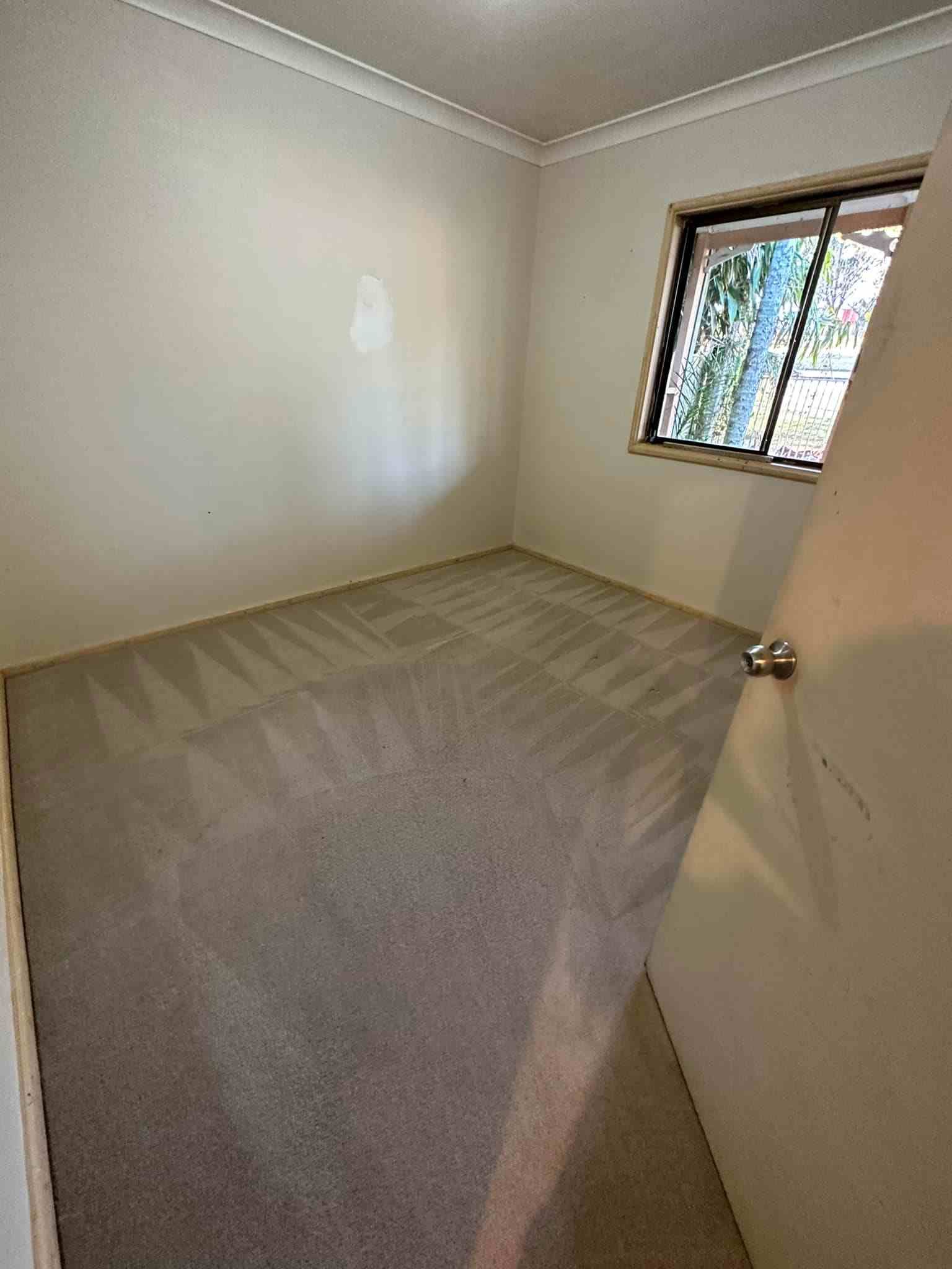 An Empty Bedroom With a Carpeted Floor and a Window — Doobies Cleaning Service in Port Macquarie, NSW