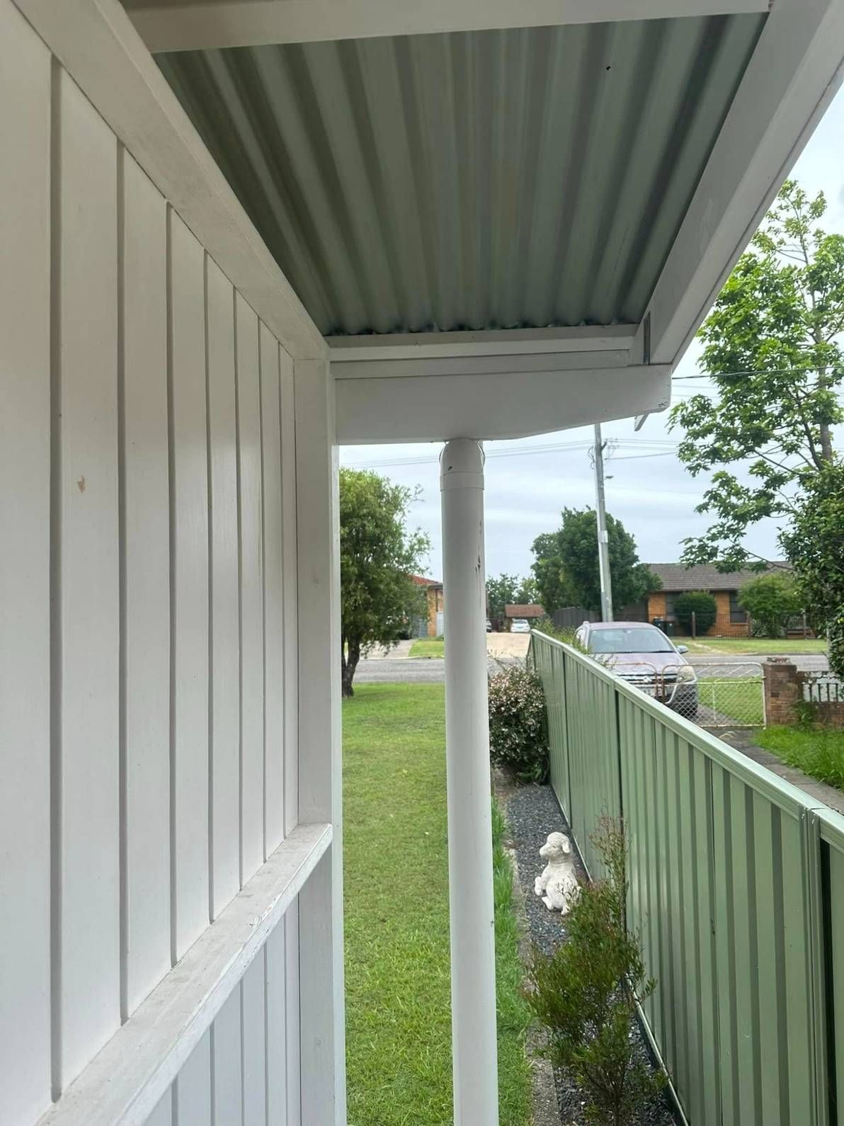 A White House With a Metal Roof and a Green Fence — Doobies Cleaning Service in Port Macquarie, NSW