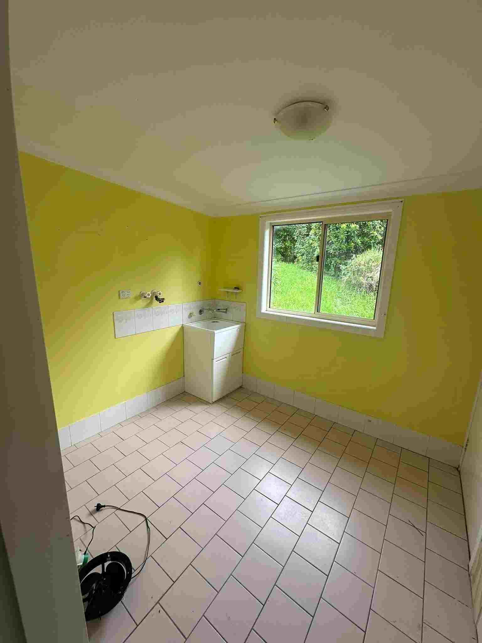 A Laundry Room With Yellow Walls , a Washer and Dryer , and a Window — Doobies Cleaning Service in Port Macquarie, NSW