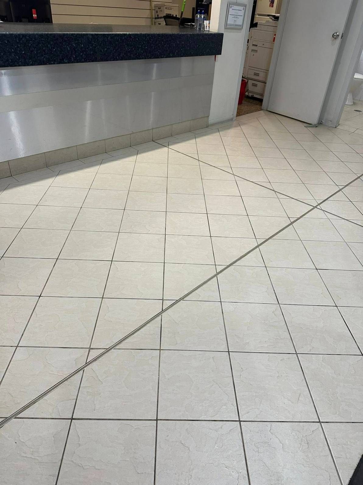 A White Tiled Floor With a Chain Going Through It — Doobies Cleaning Service in Port Macquarie, NSW