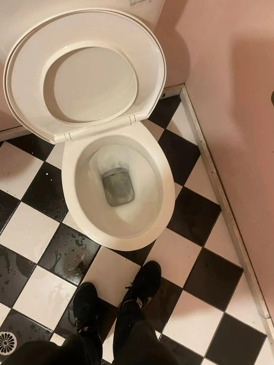 A Person Standing Next to a Toilet on a Checkered Floor — Doobies Cleaning Service in Kempsey, NSW
