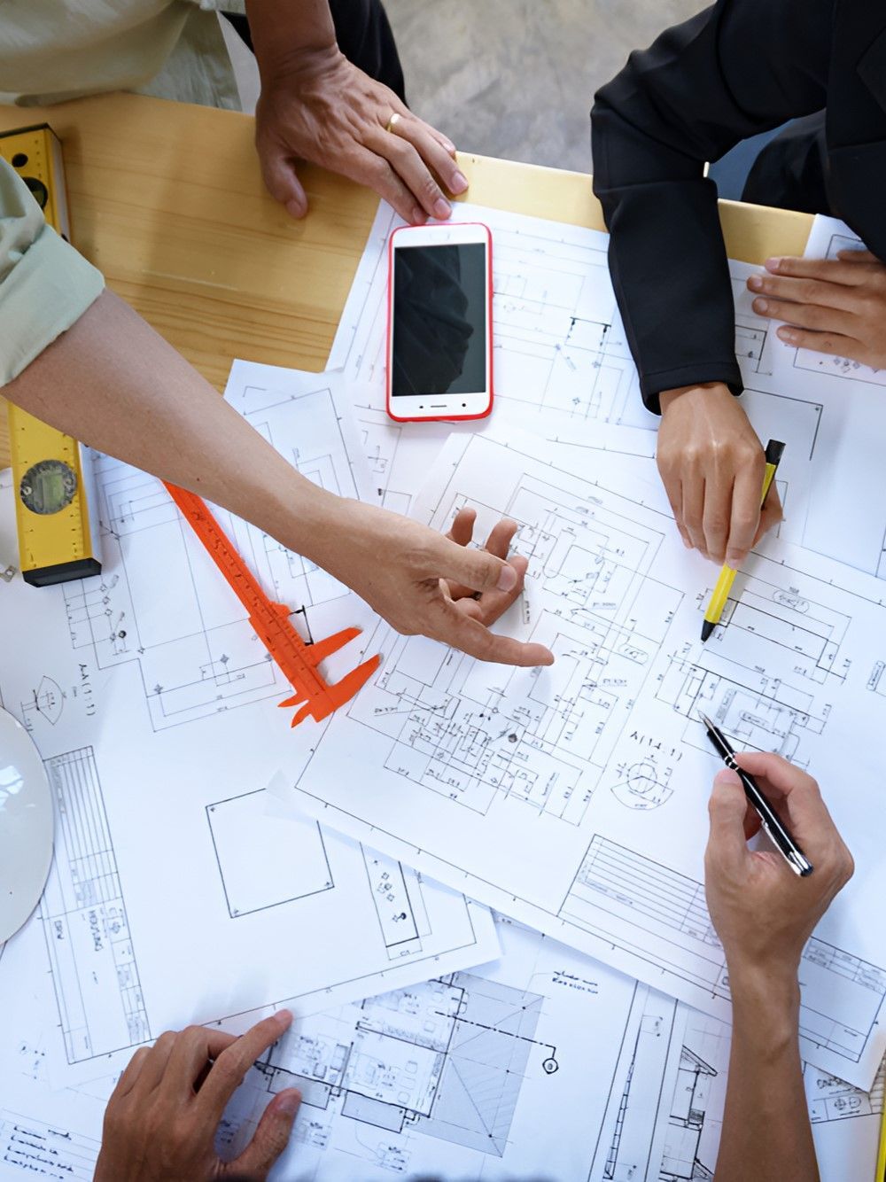 A Group Of People Are Sitting Around A Table Looking At A Blueprint — GEO – AM Consulting In Lismore, NSW