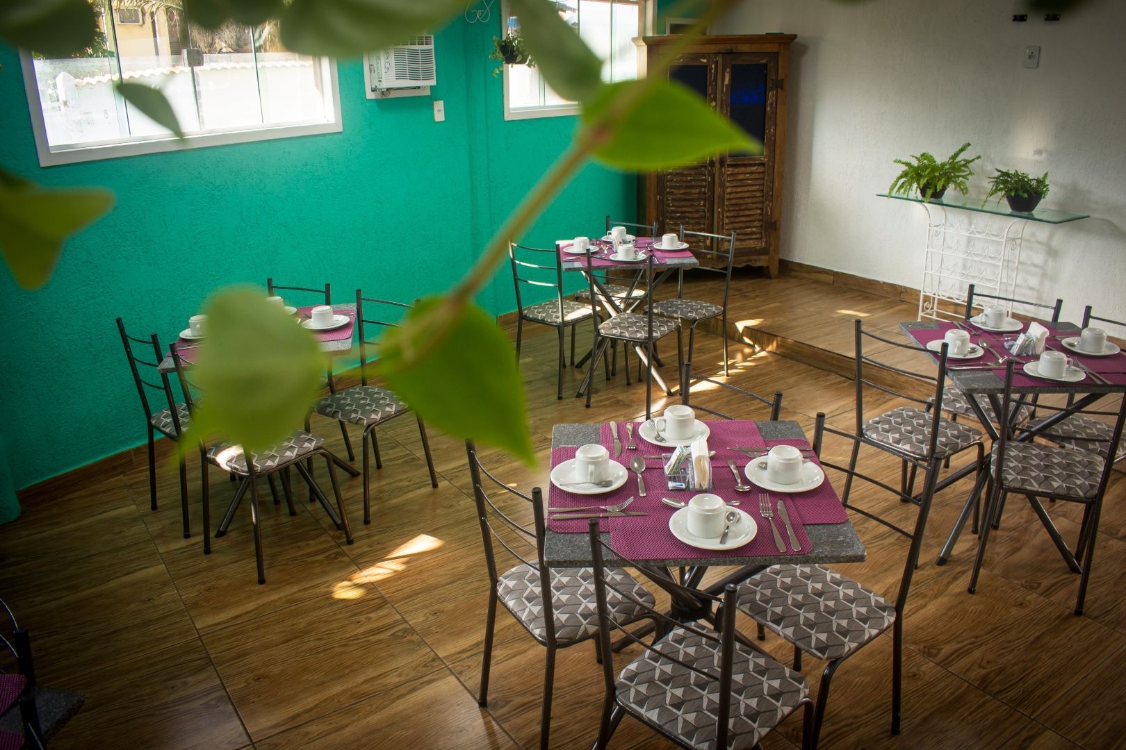 Uma sala de jantar com mesas e cadeiras e uma parede verde.
