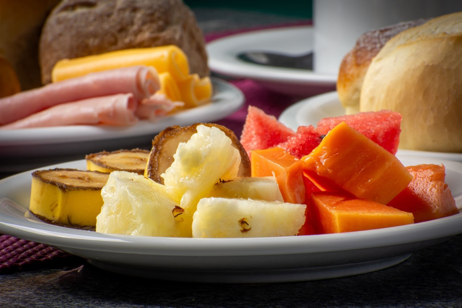 Um prato branco coberto com fatias de frutas e presunto sobre uma mesa.