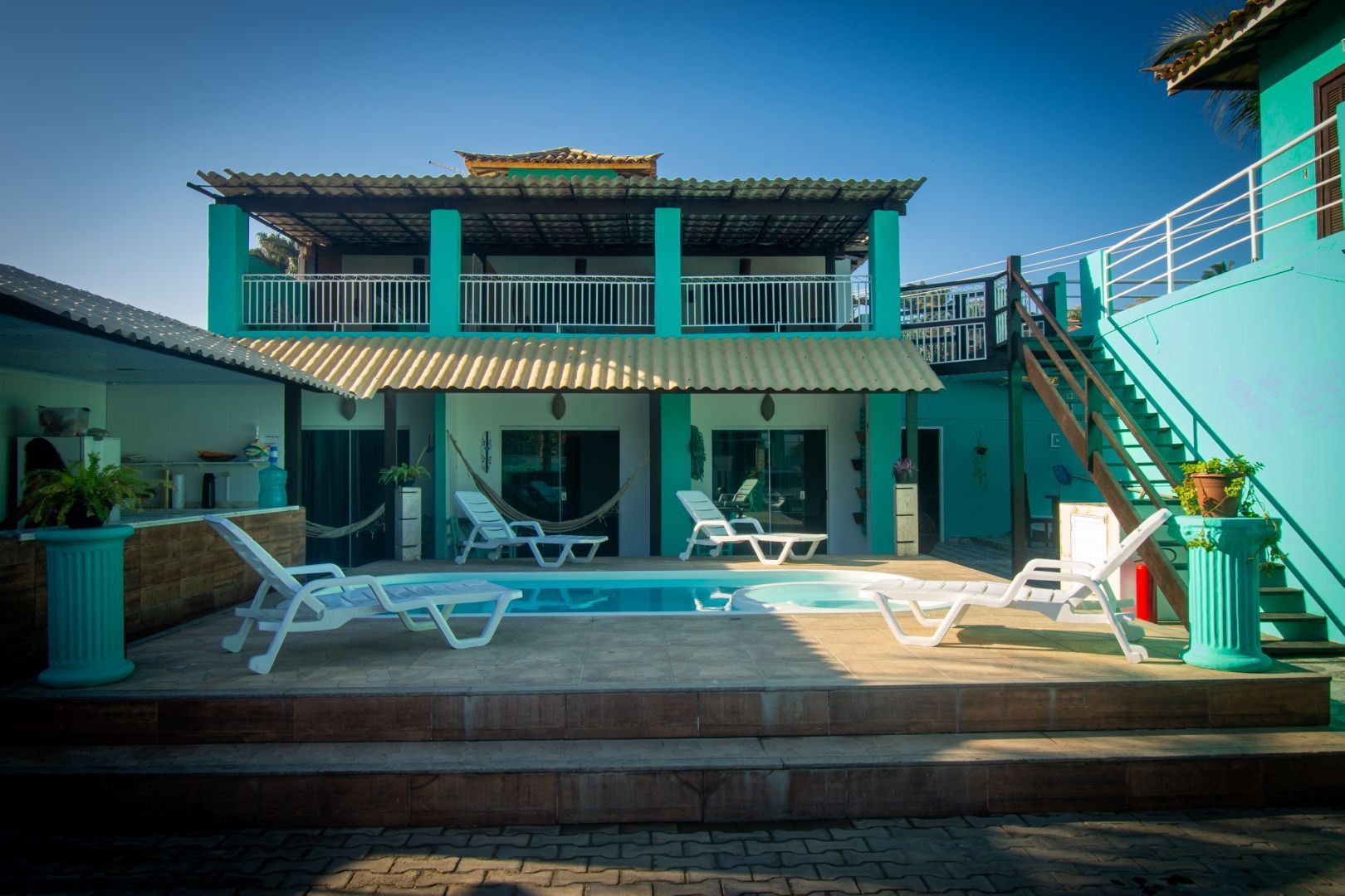 Uma grande casa azul com uma piscina na frente.