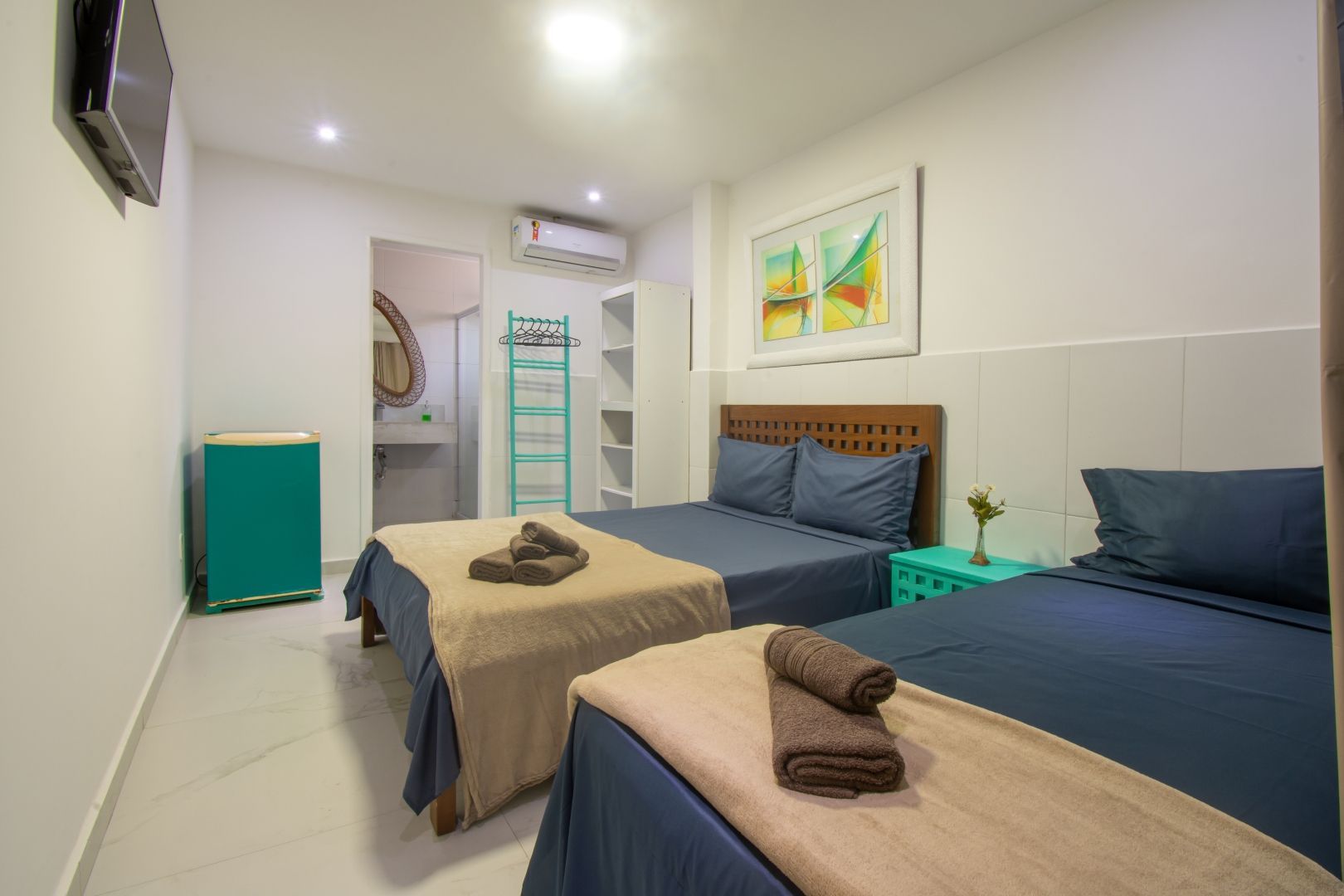 Um quarto de hotel com três camas e uma televisão.