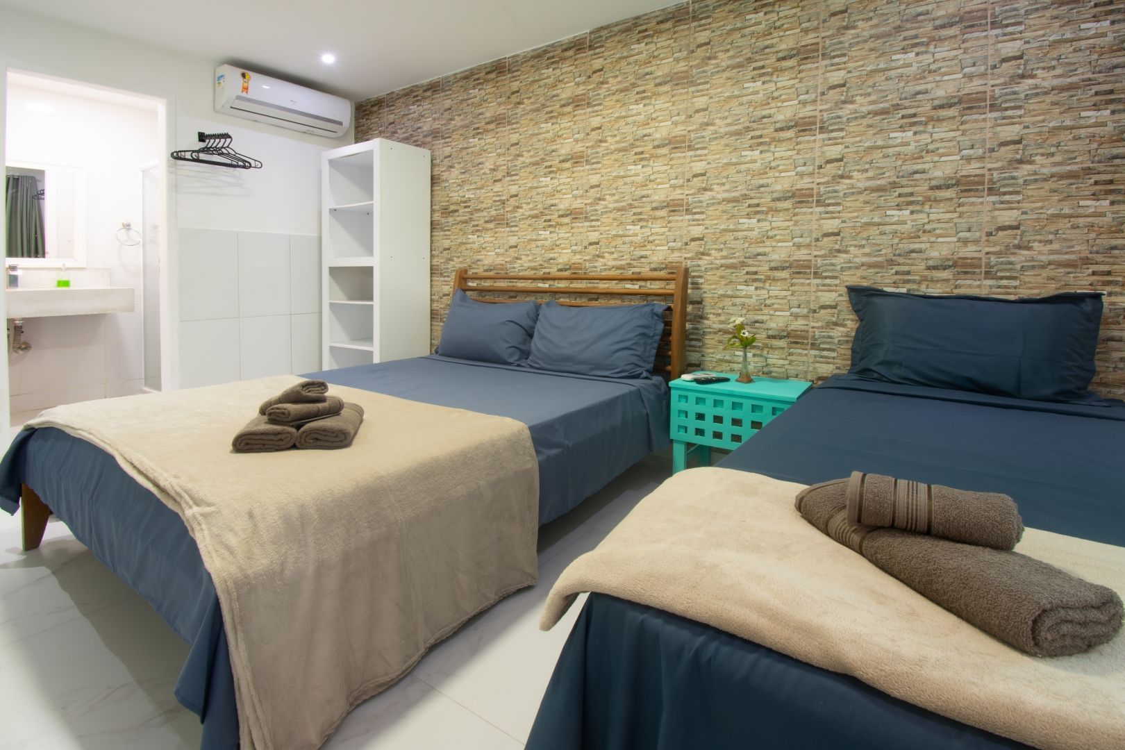 Um quarto com duas camas e uma parede de tijolos.