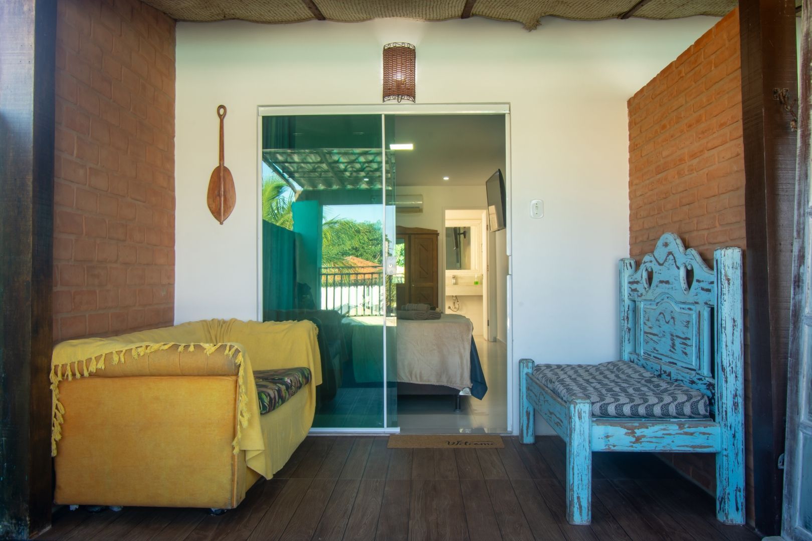 Uma varanda com um sofá, cadeira e portas de vidro deslizantes que levam a um quarto.