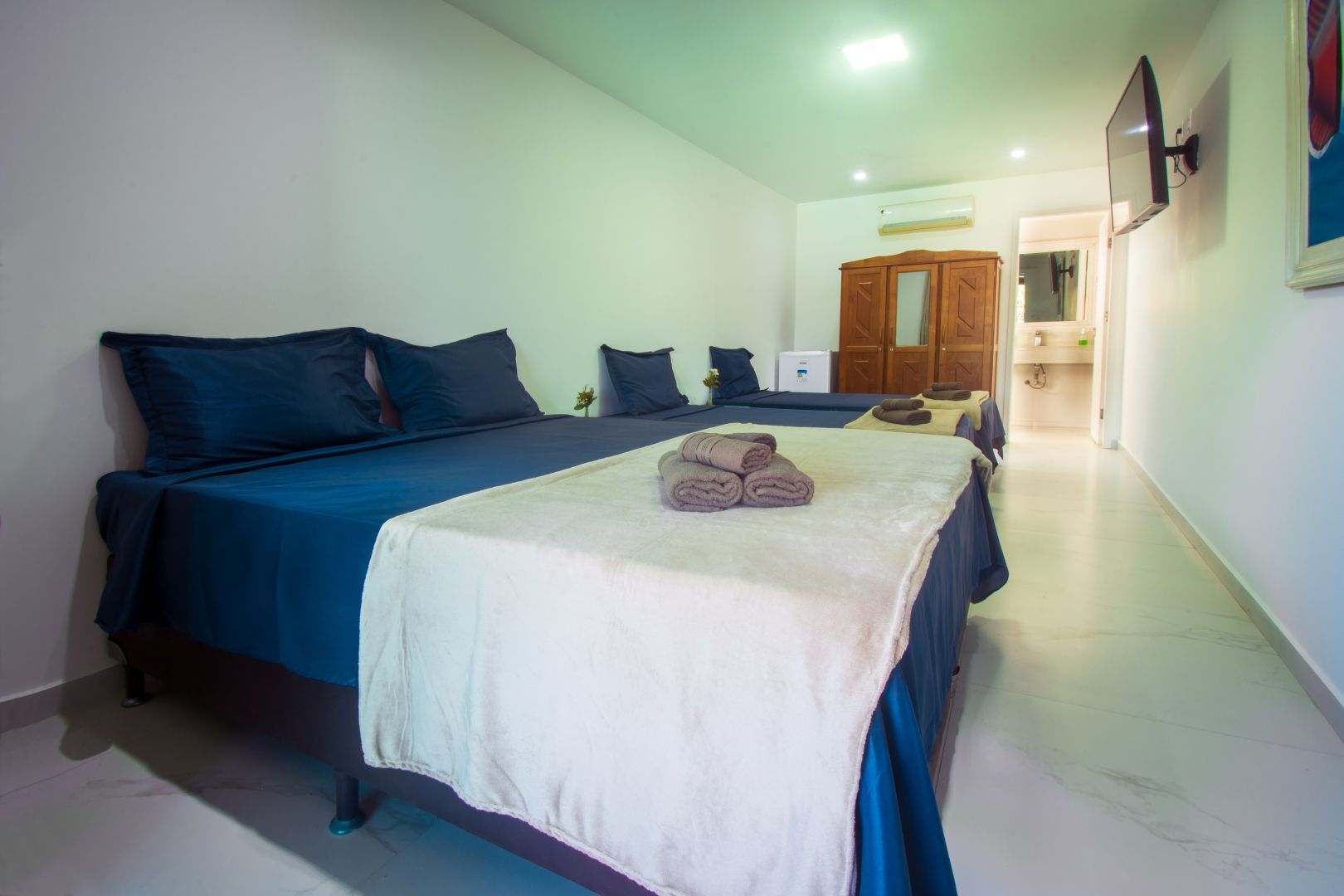 Um quarto de hotel com três camas e uma TV de tela plana.