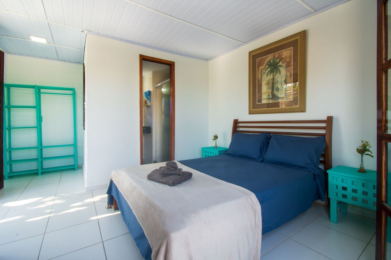 Um quarto com uma cama, duas mesas de cabeceira e um quadro na parede.