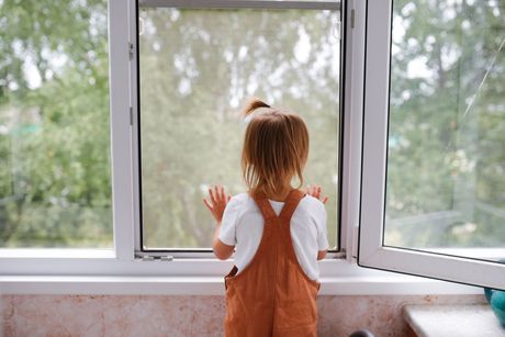 Una bambina guarda fuori dalla finestra.