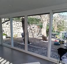 Un soggiorno con molte finestre e un albero sullo sfondo.