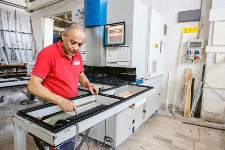 Un uomo con una camicia rossa sta lavorando a una macchina in una fabbrica.