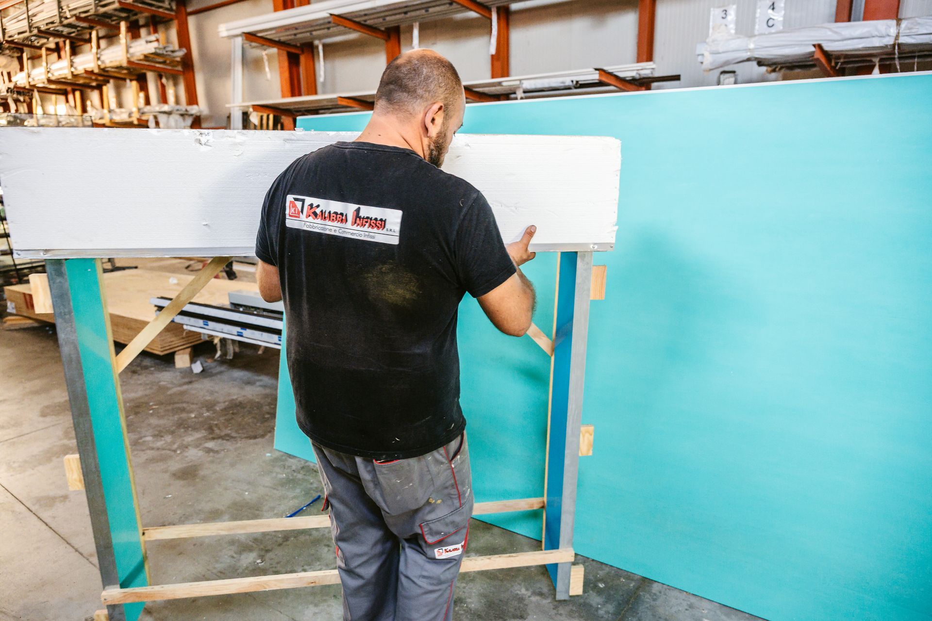 Un uomo con una camicia nera sta lavorando su un pezzo di legno in un magazzino.