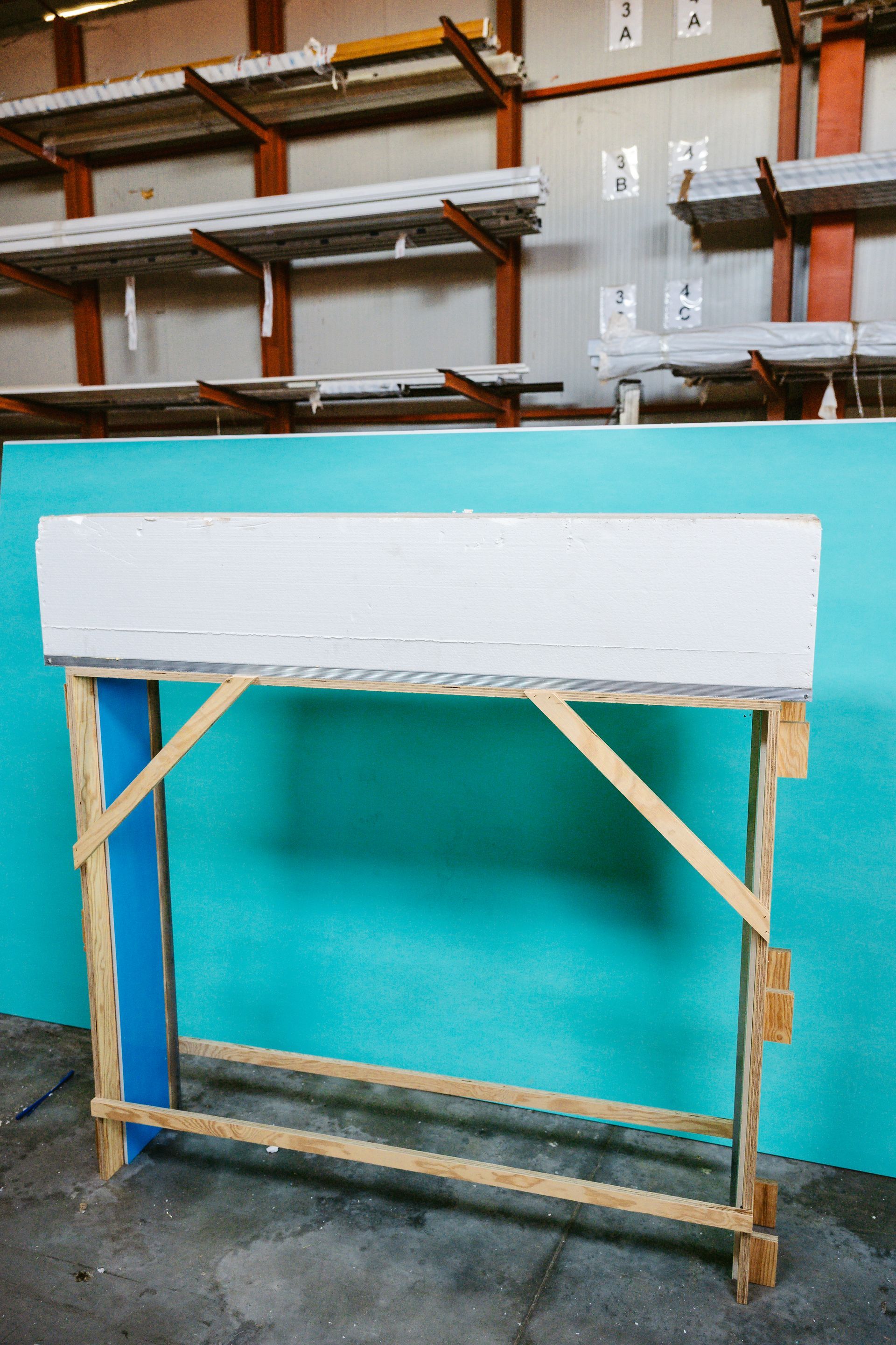 Un grande pezzo di polistirolo è appoggiato su un supporto di legno in un magazzino.