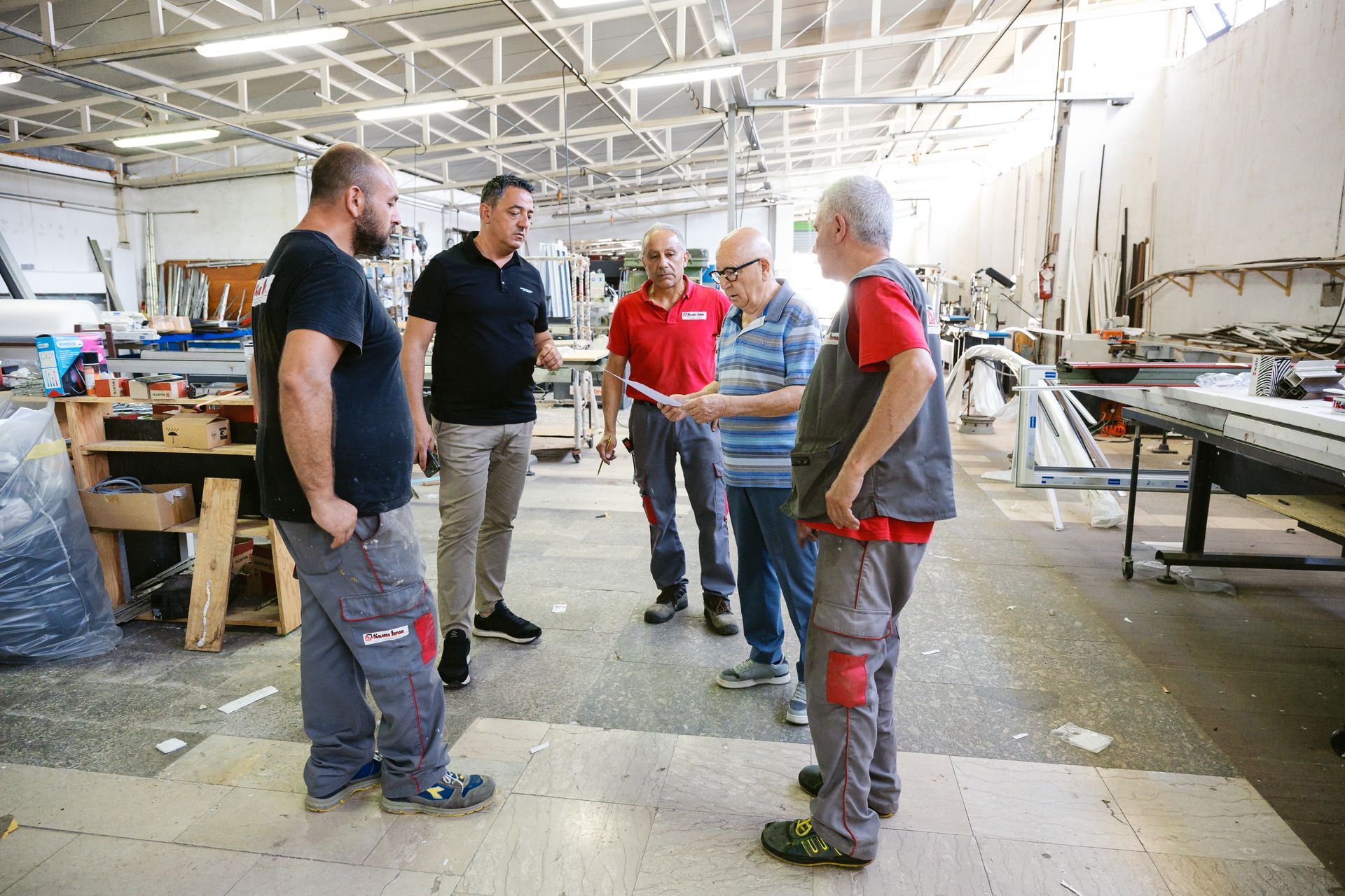 Un gruppo di uomini è in piedi in un magazzino e parla tra loro.