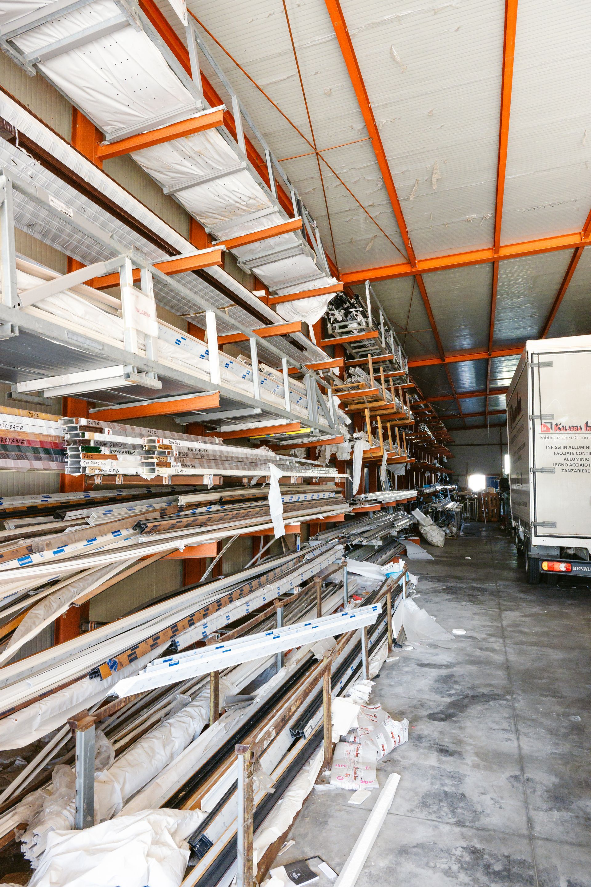 Un magazzino pieno di scaffali e un camion parcheggiato sullo sfondo.