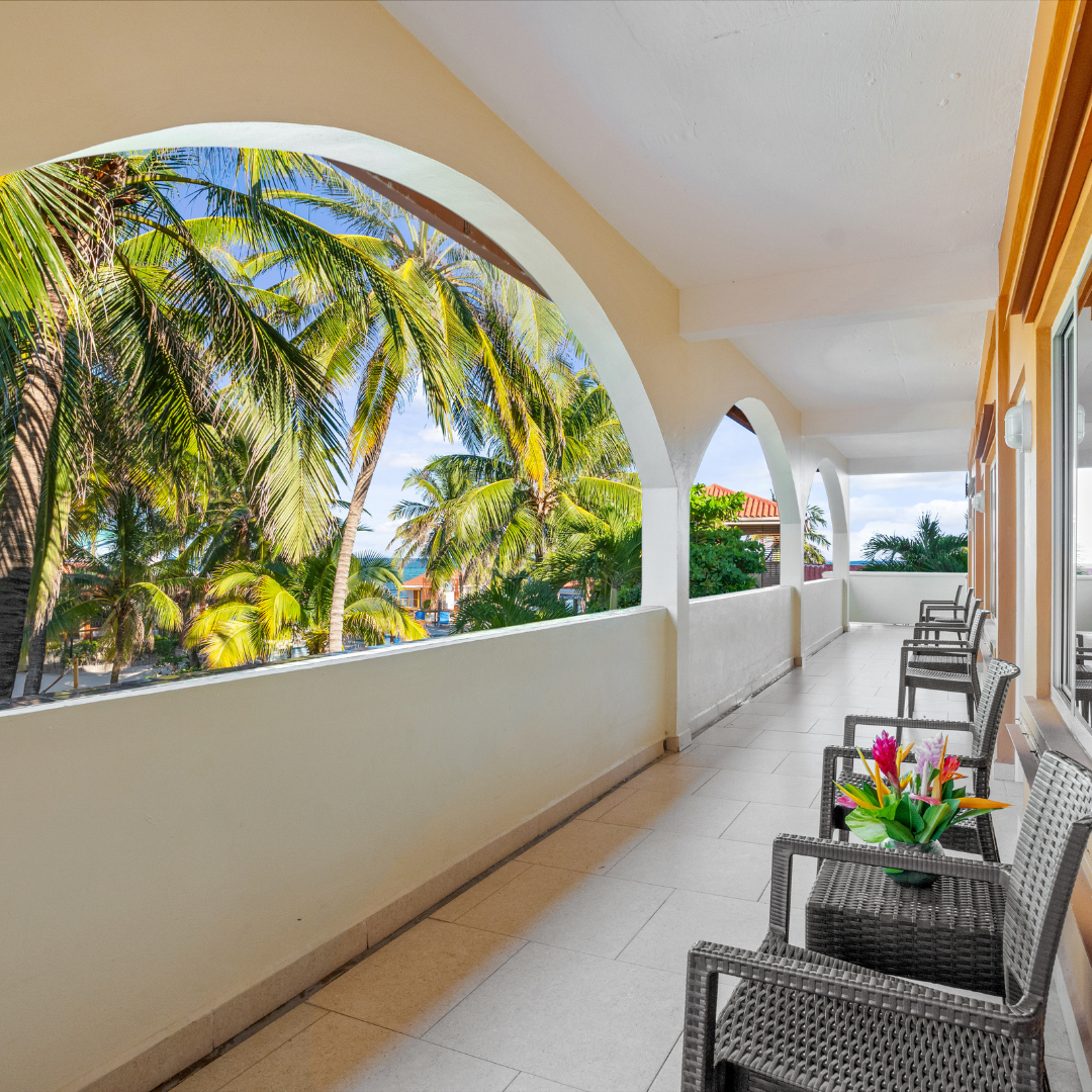 A balcony with a view of palm trees and a table and chairs
