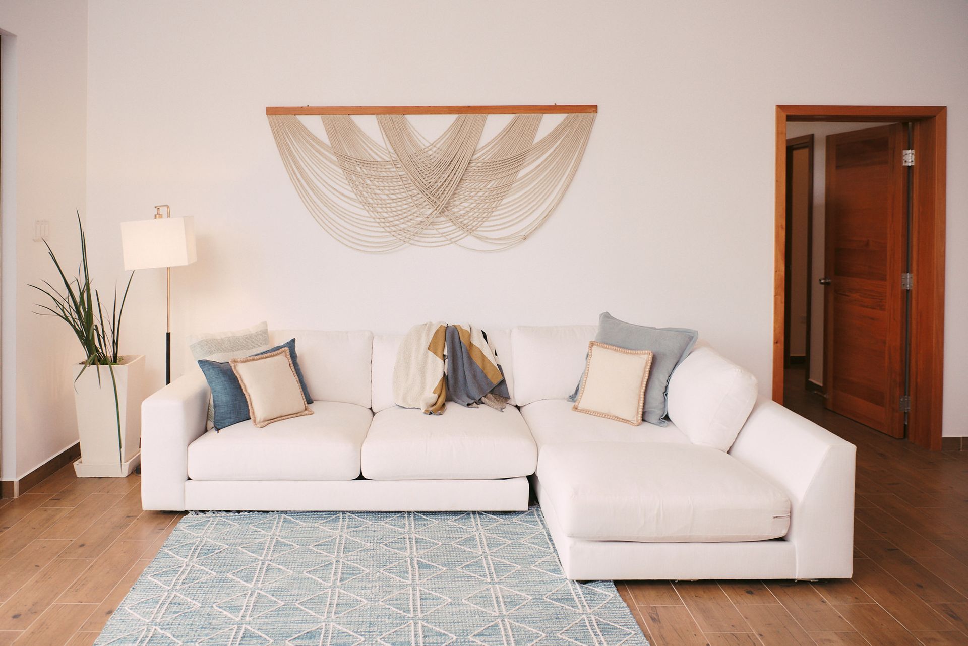 a living room with a white sectional couch and a blue rug .