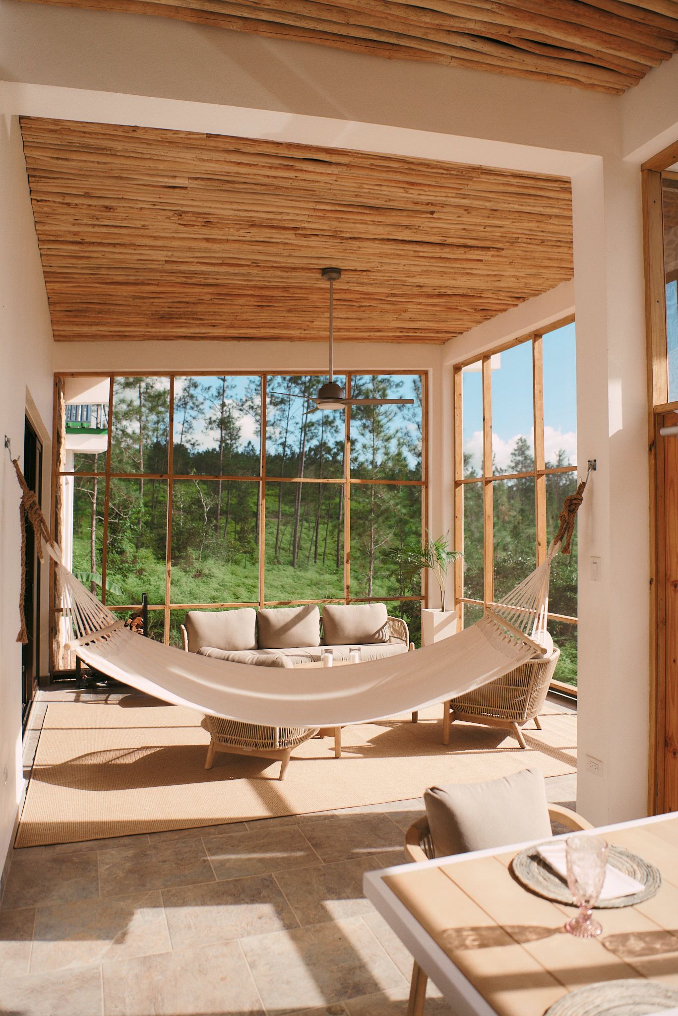 A living room with a hammock hanging from the ceiling and a couch.