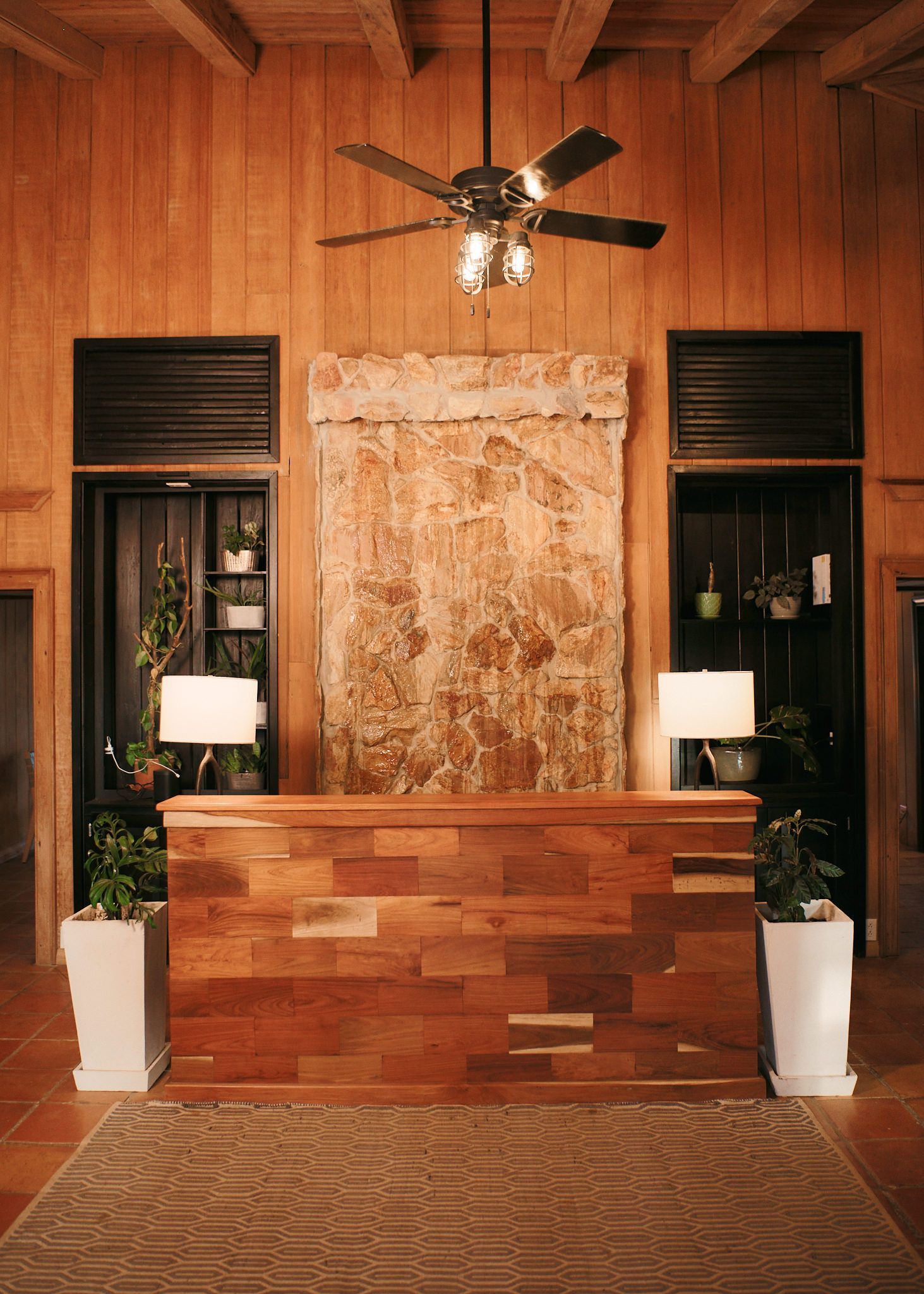 there is a wooden table in the middle of the room with a ceiling fan .