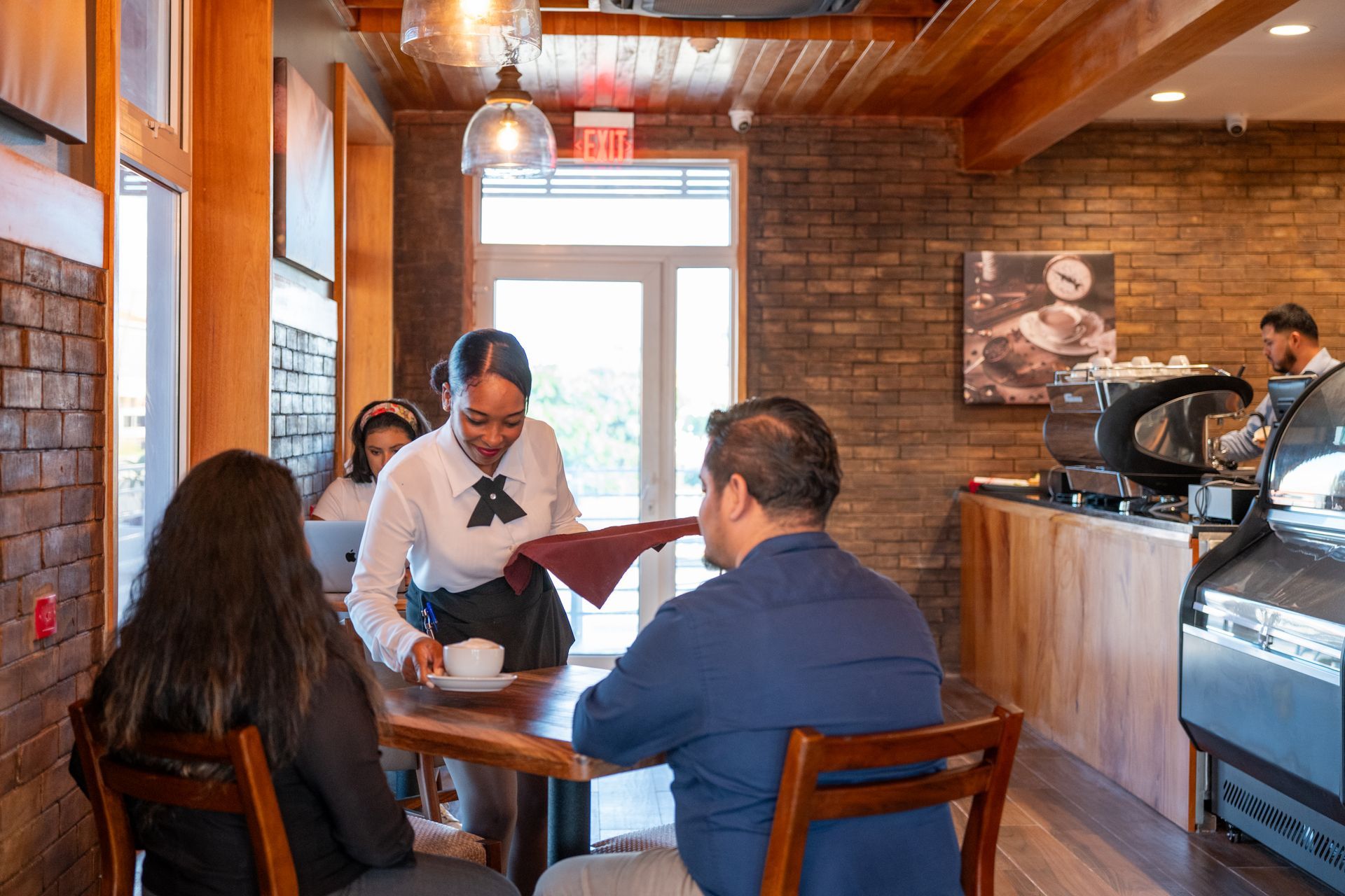 A woman is serving a man and a woman at a table in a restaurant.