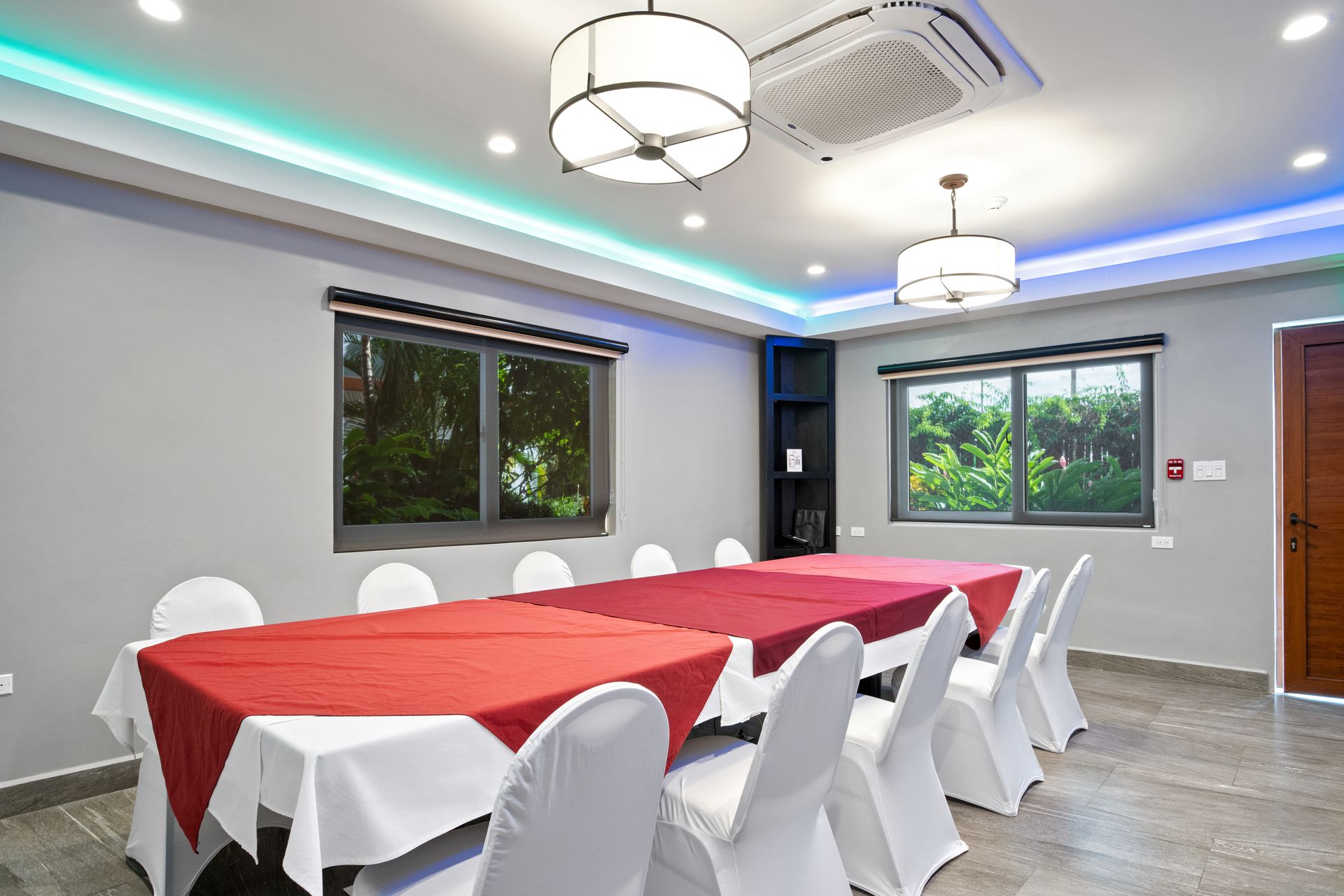 A long table with a red tablecloth and white chairs in a room.