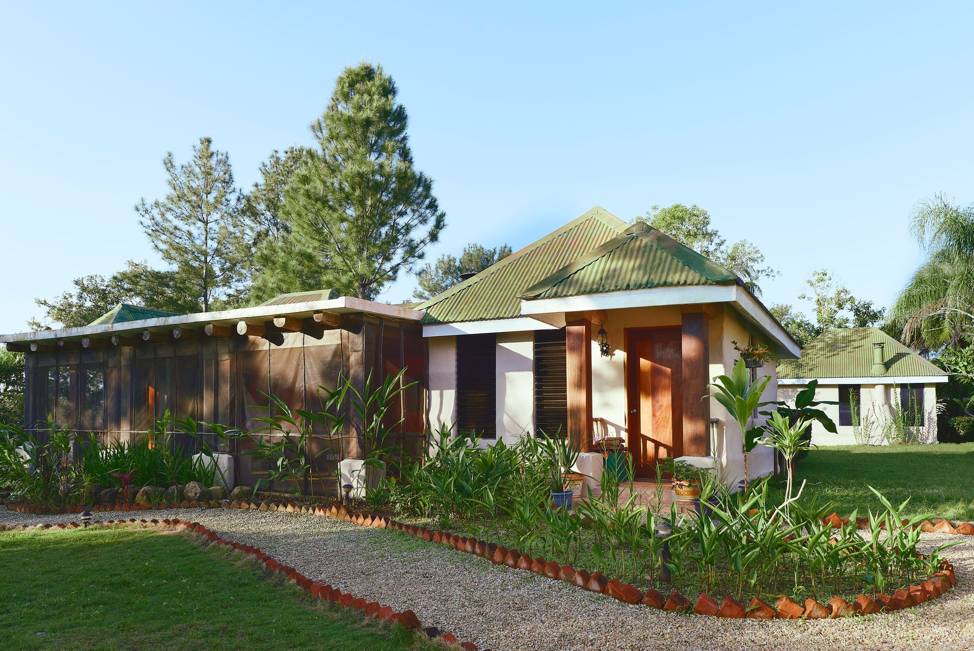 A house with a green roof is surrounded by grass and trees