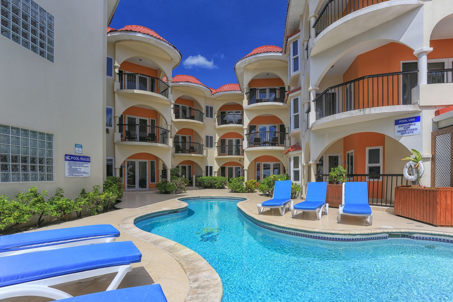 a large swimming pool surrounded by chairs in front of a building .