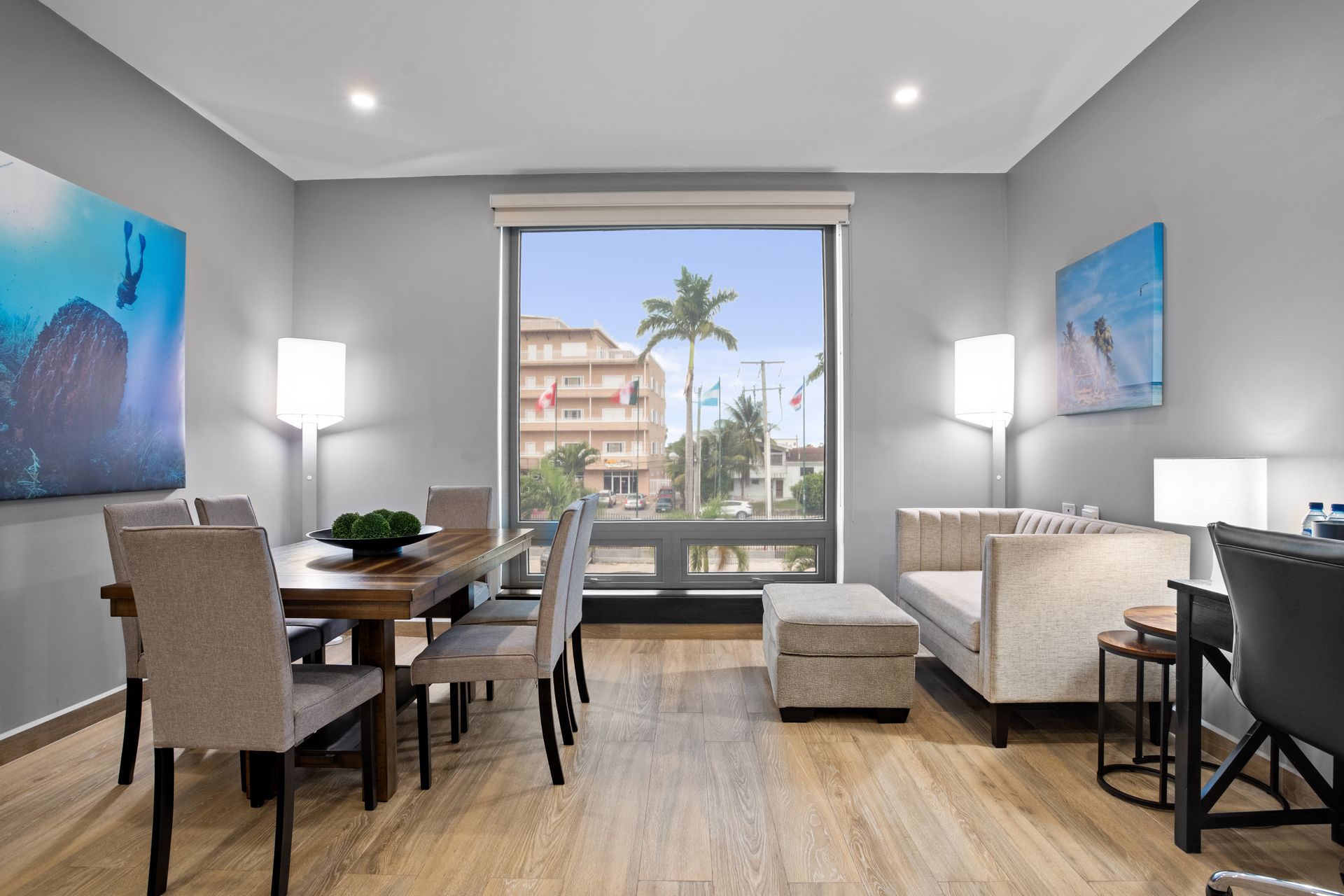 A living room with a dining table and chairs and a large window.
