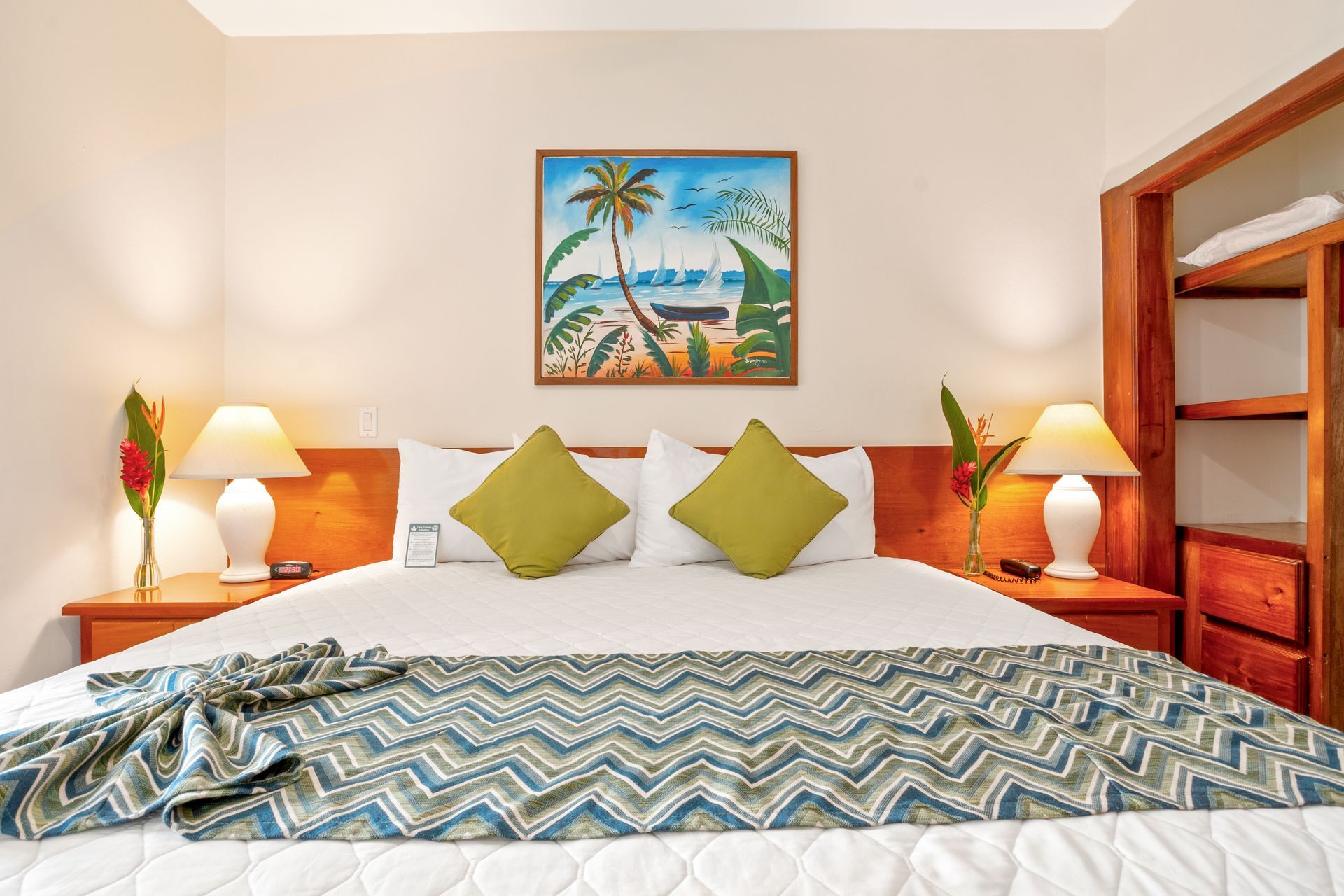 A hotel room with a king size bed and a painting on the wall above it.