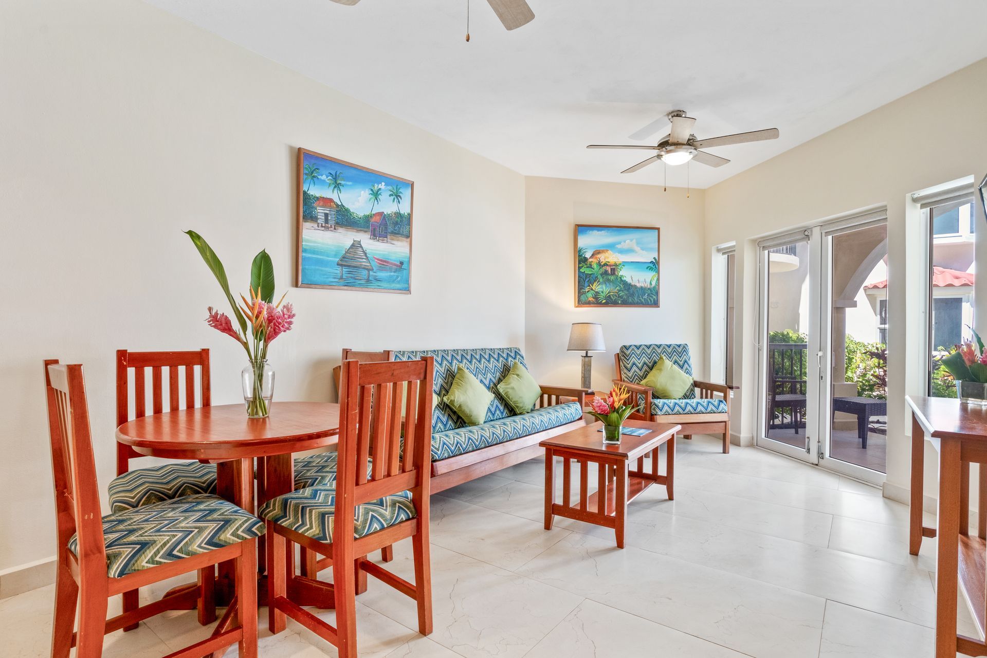 A living room with a couch , table , chairs and a ceiling fan.