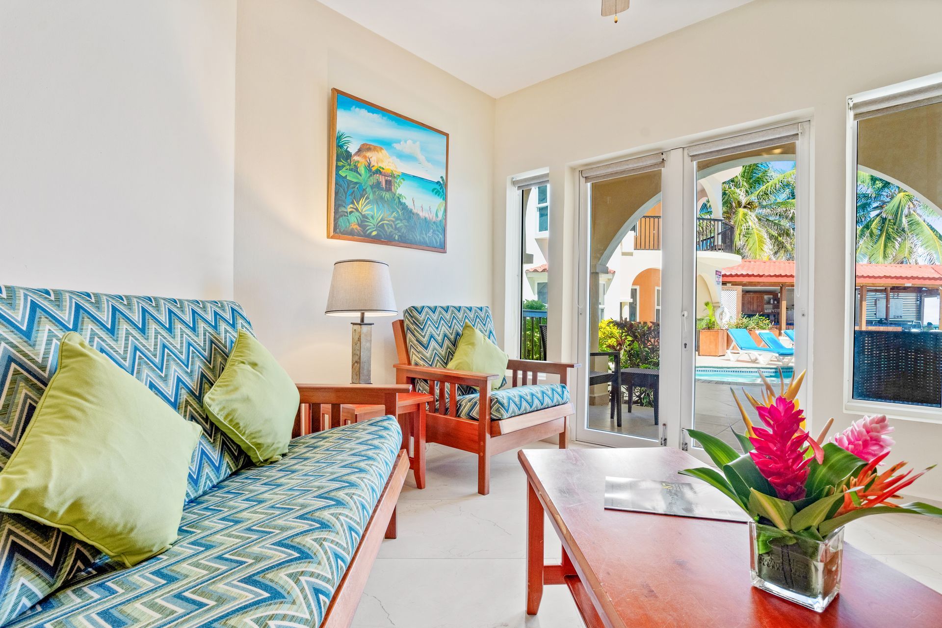 A living room with a couch , chairs , table and a painting on the wall.