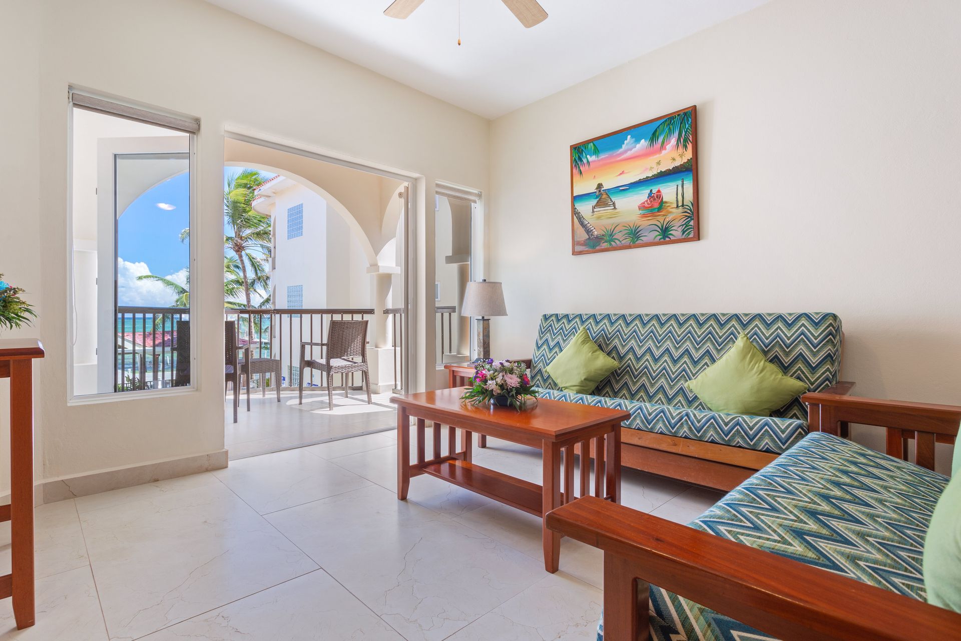 A living room with a couch , chairs , coffee table and a balcony.