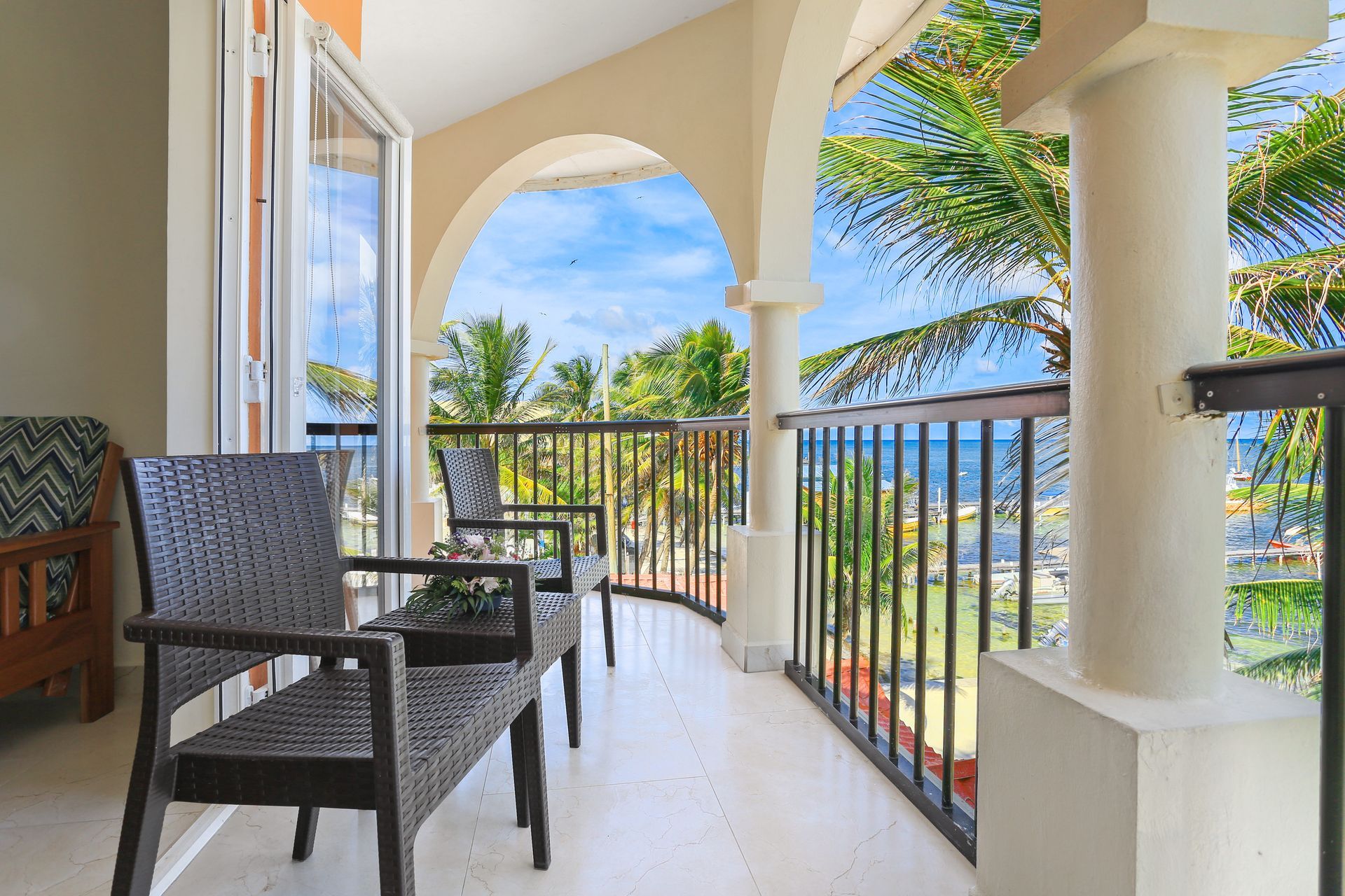 A balcony with chairs and a table with a view of the ocean.