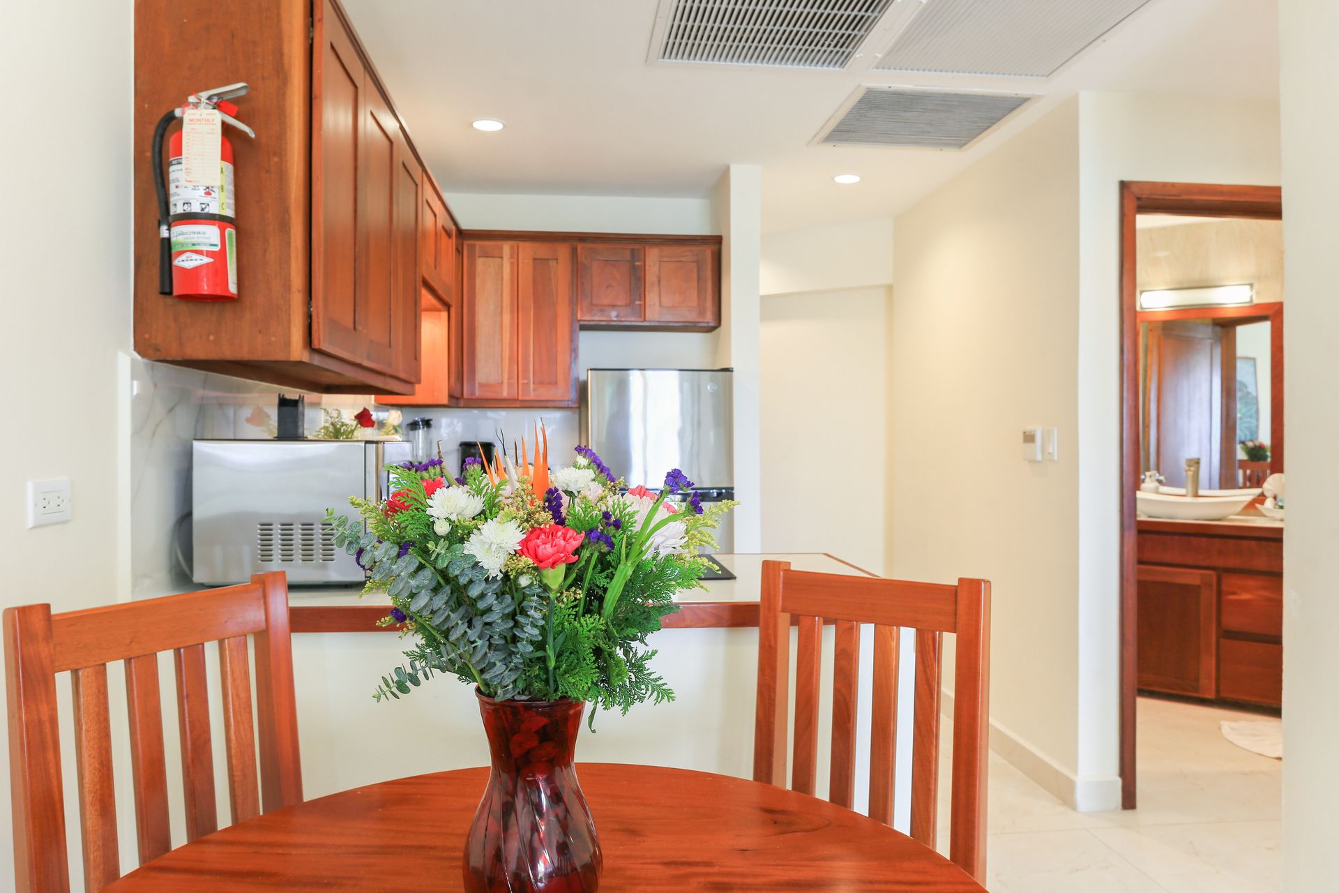 There is a vase of flowers on the table in the kitchen.