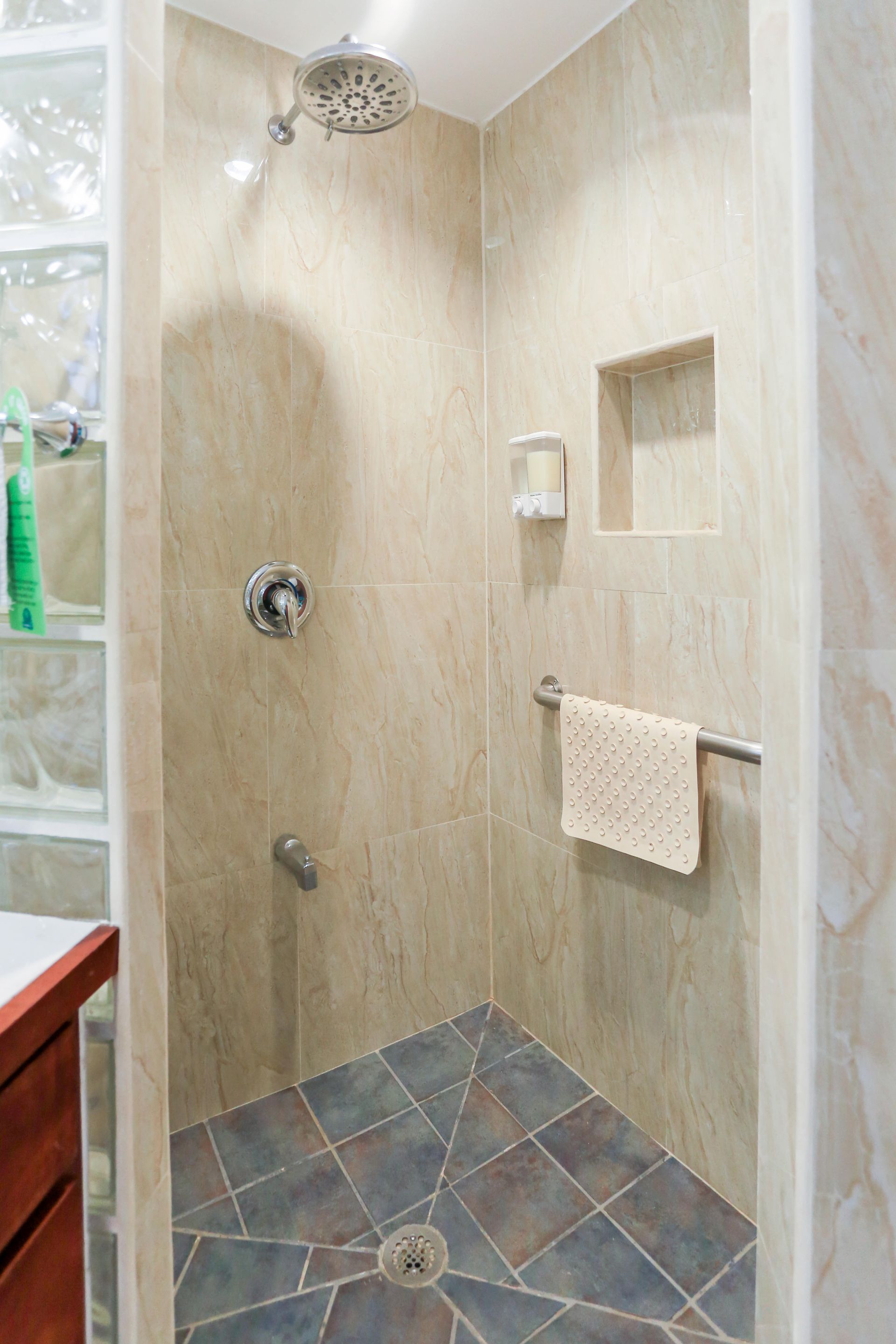 A bathroom with a walk in shower and a sink.