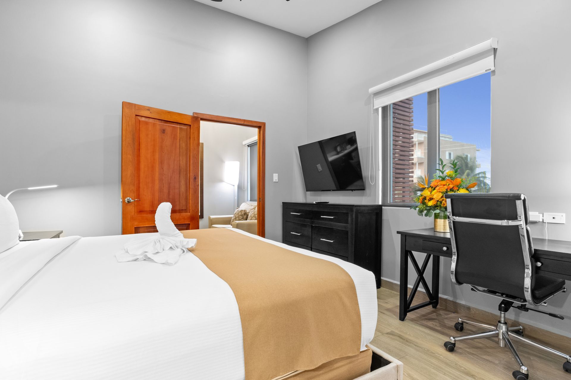 A hotel room with a king size bed , desk , chair and television.