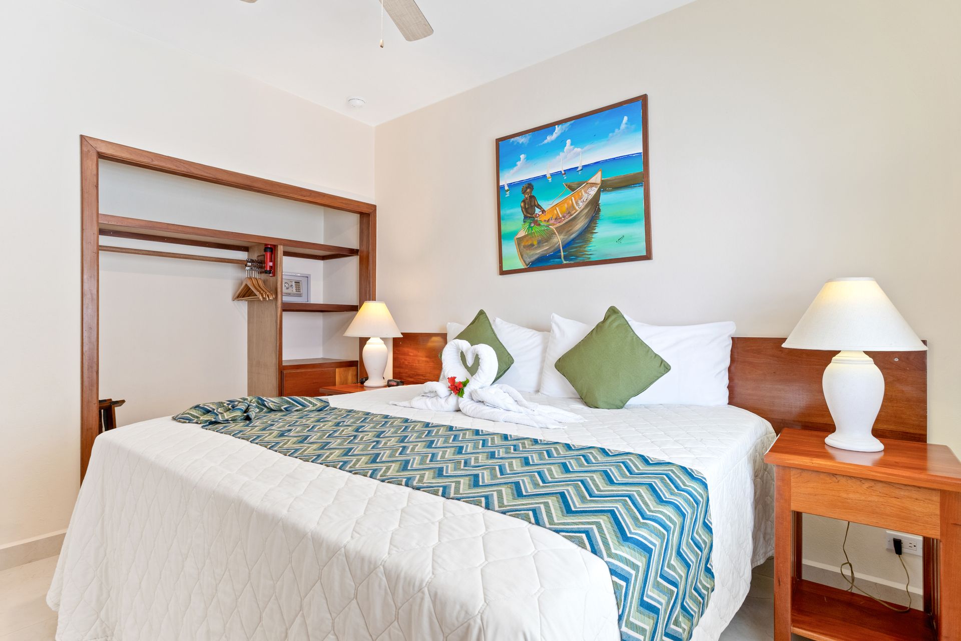 A hotel room with a large bed , two lamps and a painting on the wall.