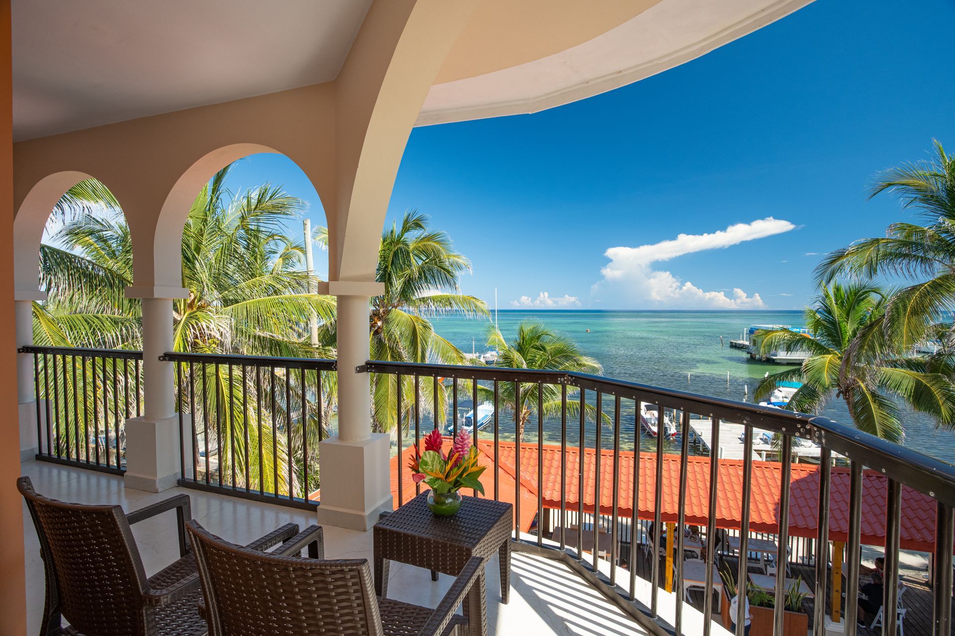 A balcony with two chairs and a table overlooking the ocean.