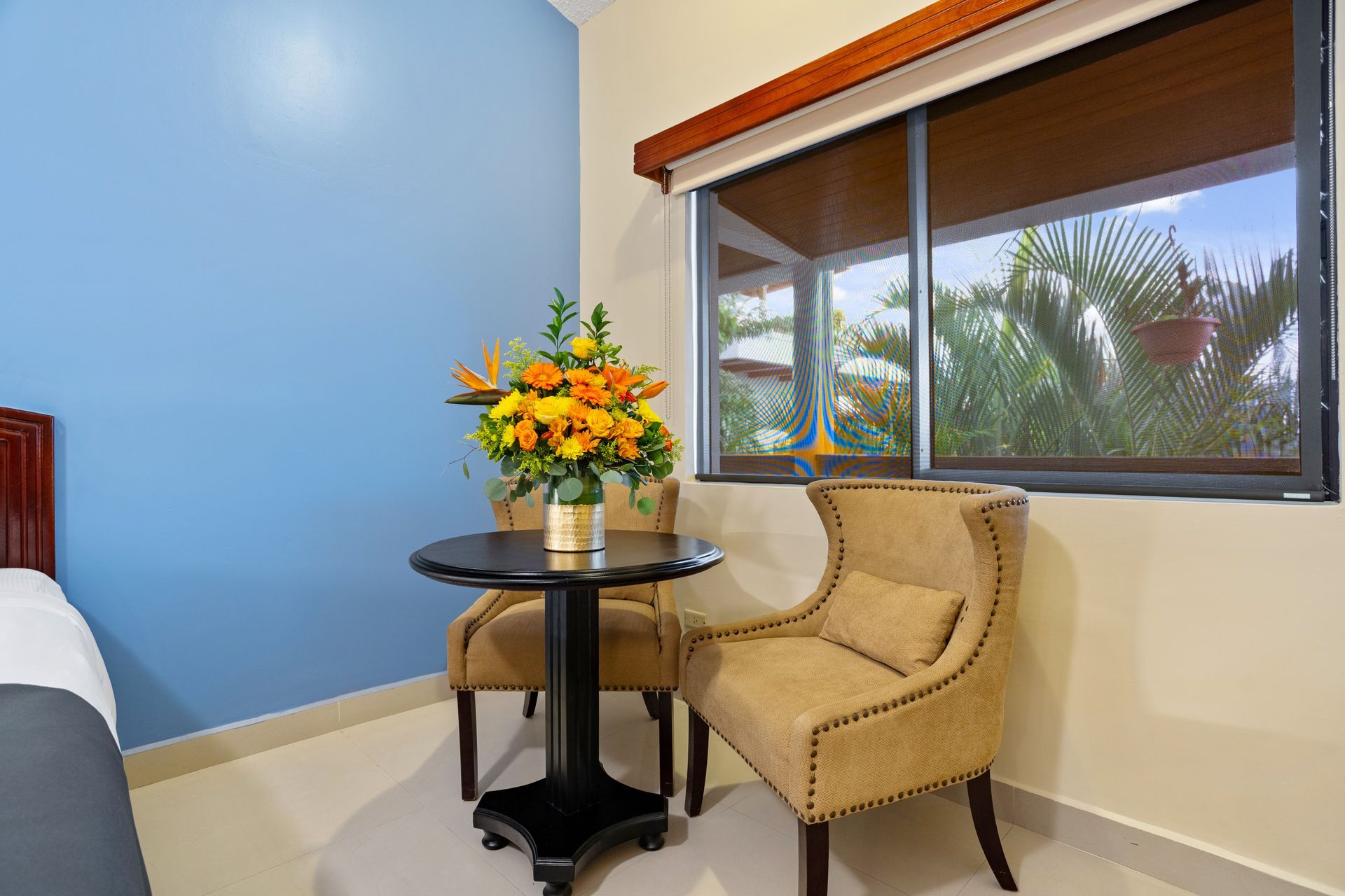 A hotel room with two chairs and a table with a vase of flowers on it.