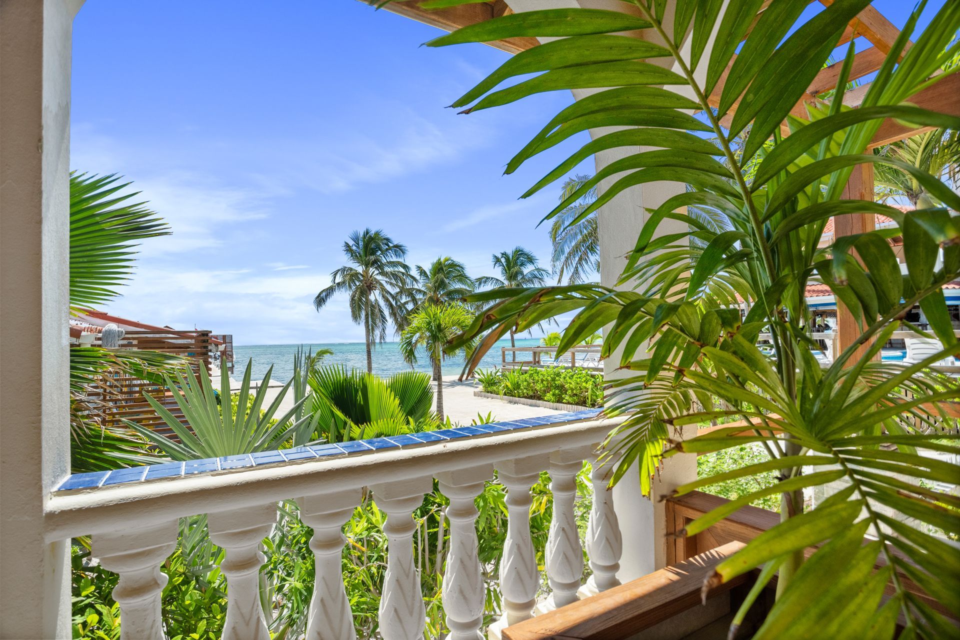 A balcony with a view of the ocean and palm trees