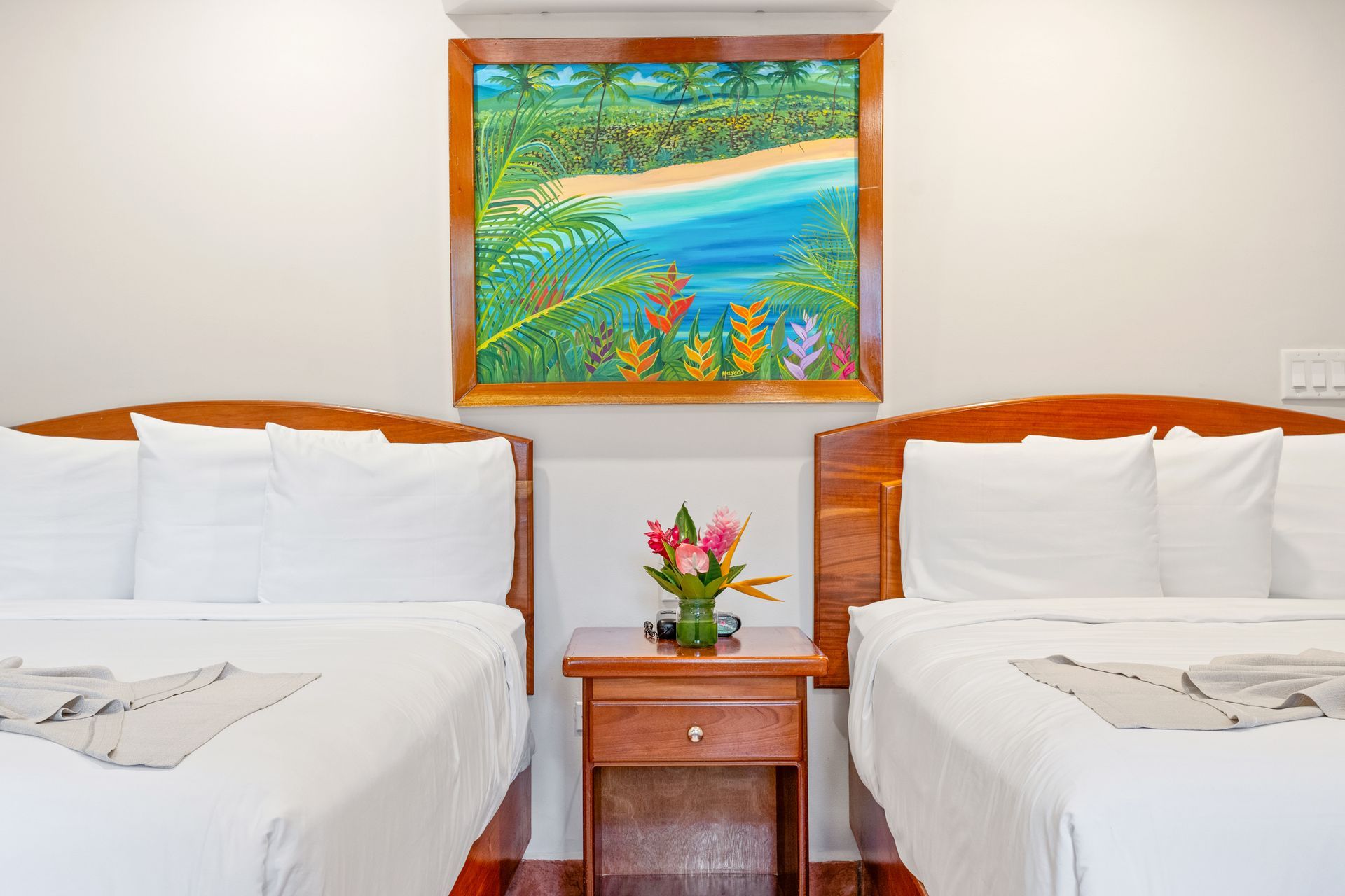 A hotel room with two beds , a nightstand and a painting on the wall.