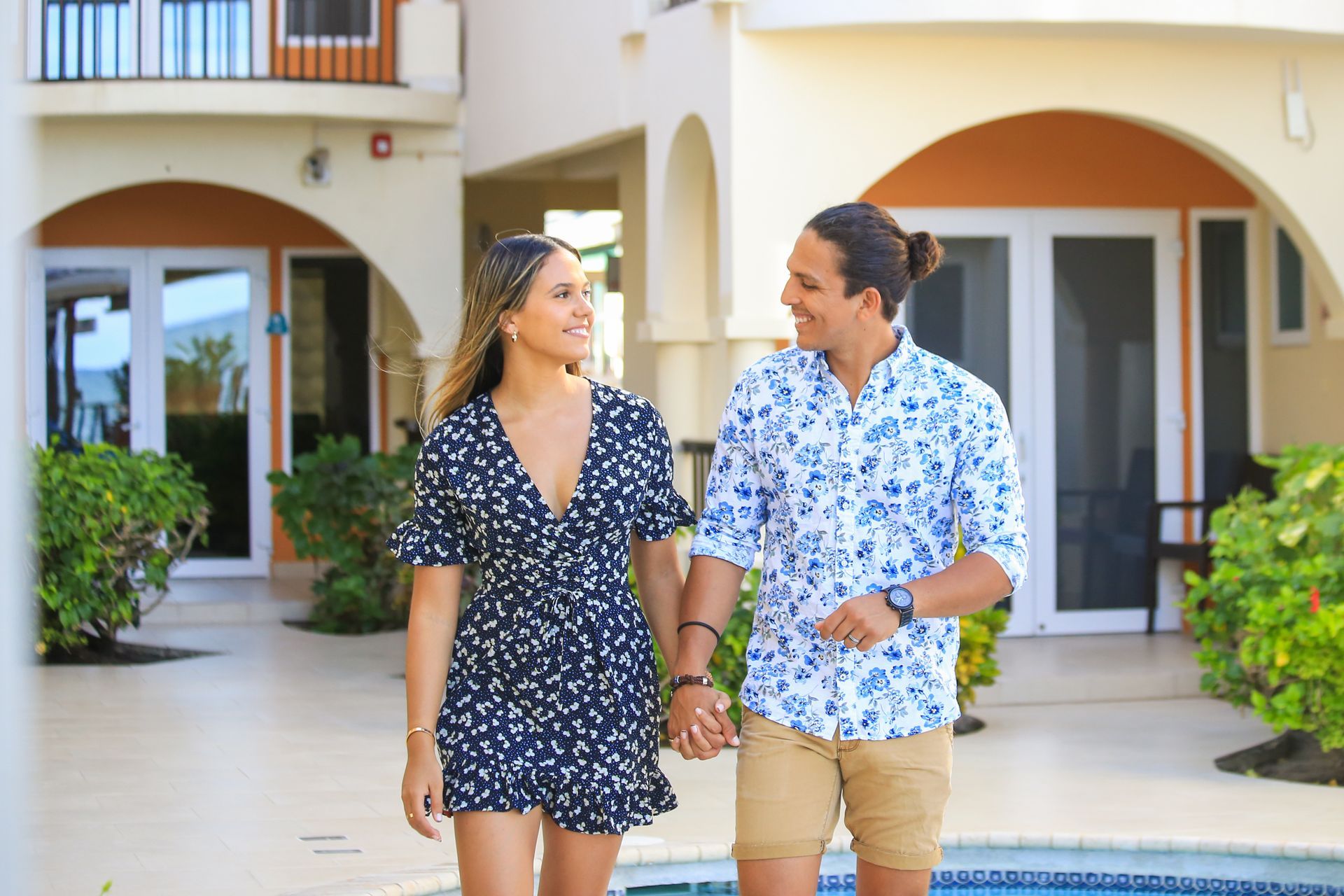 a man and a woman are holding hands while standing next to a pool .