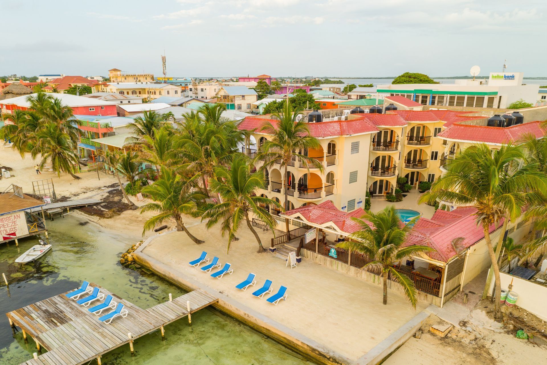an aerial view of a beach resort with palm trees and a dock .