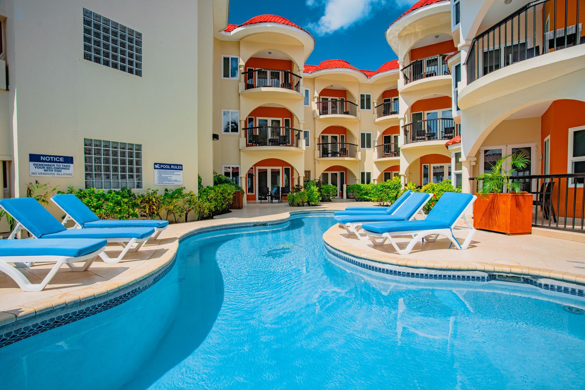 A large swimming pool surrounded by lounge chairs in front of a building.
