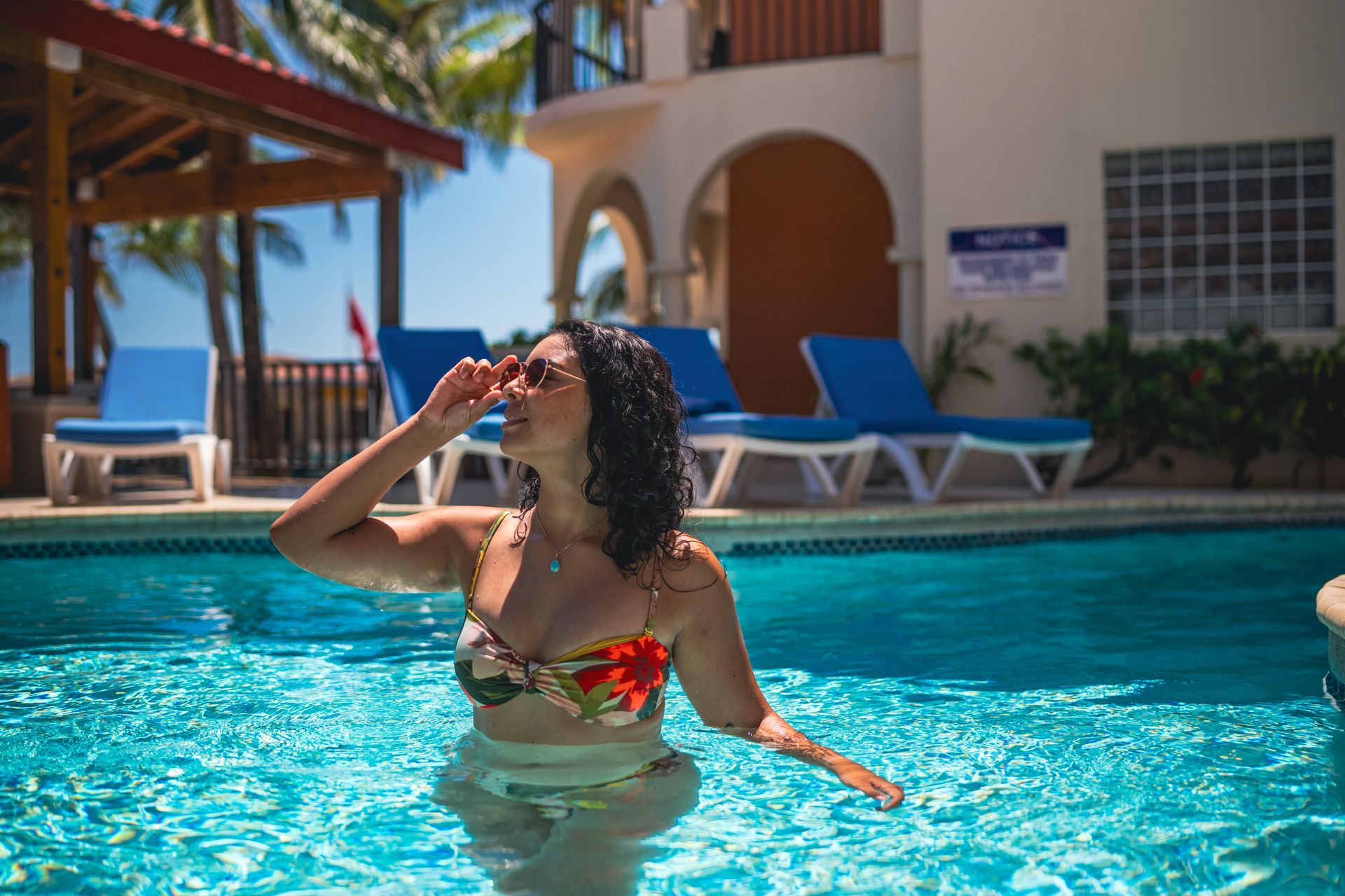 A woman in a bikini is sitting in a swimming pool.